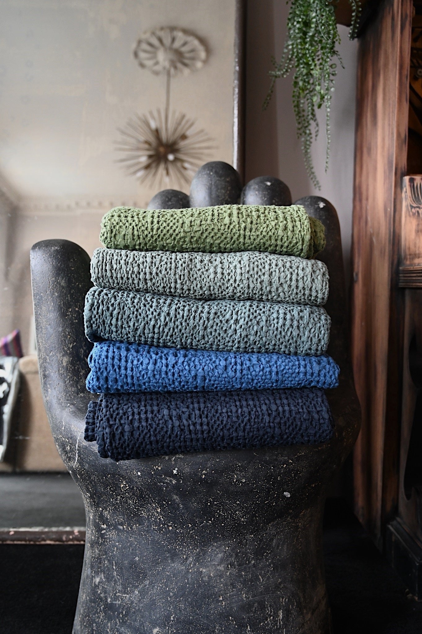 Stack of rolled stonewashed cotton throws in green and blue waffle weave.