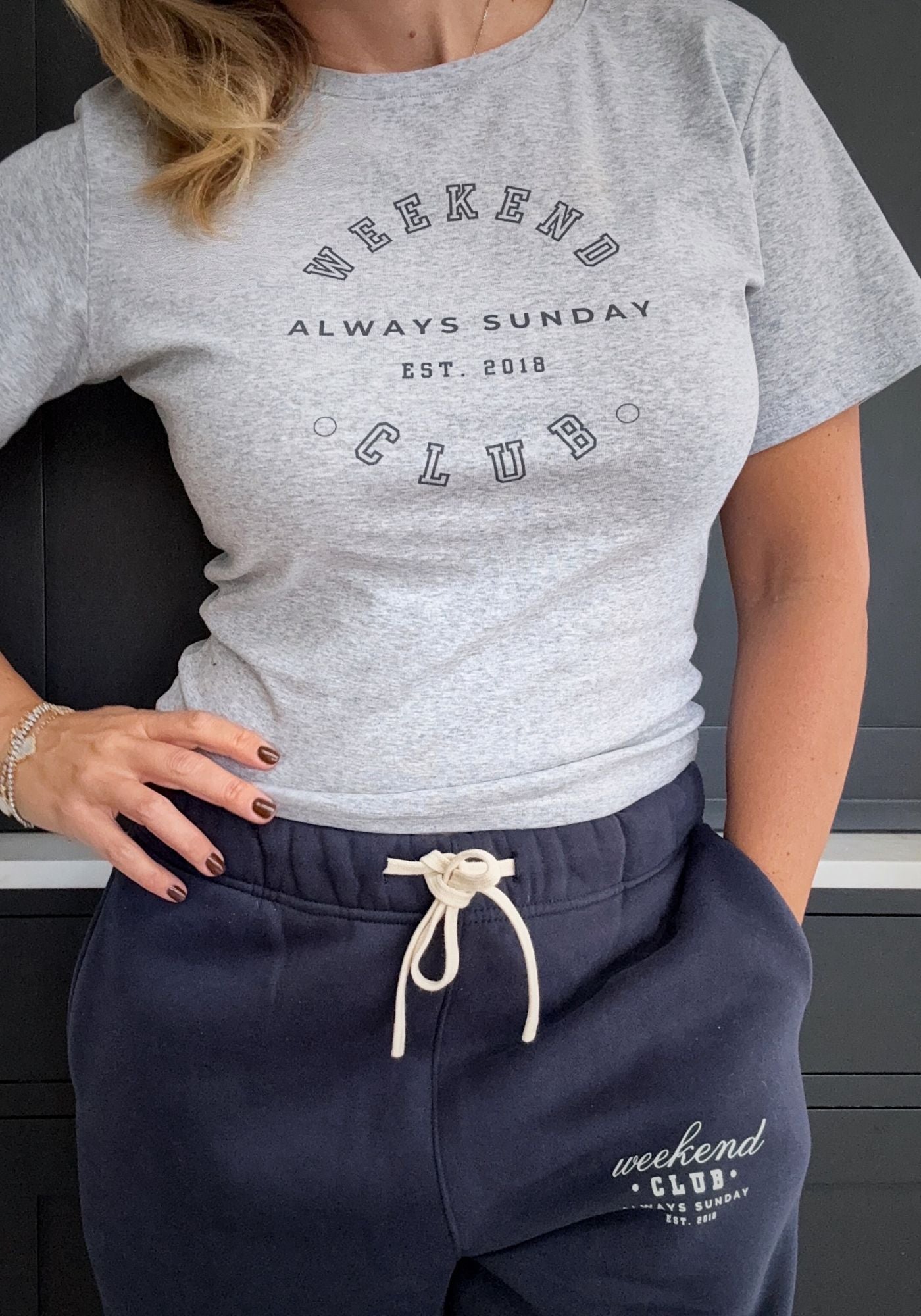 Person wearing a gray t-shirt with 'Weekend Club' text and navy pants with a matching drawstring.
