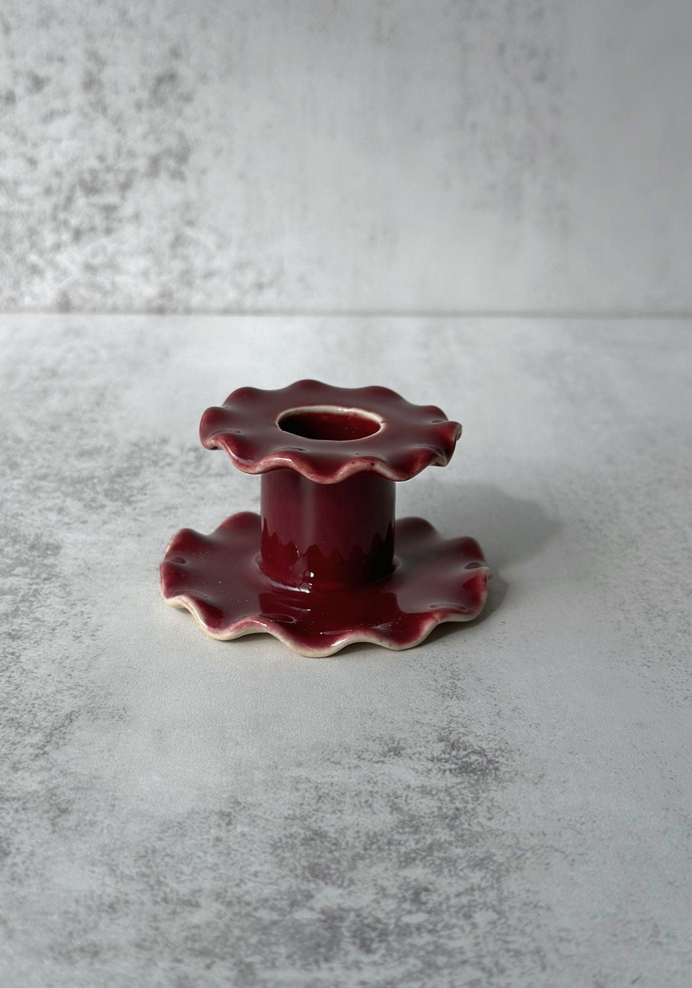 Hand-thrown ceramic candle holders with ruffled edges in blue, pink, and yellow glazes.
