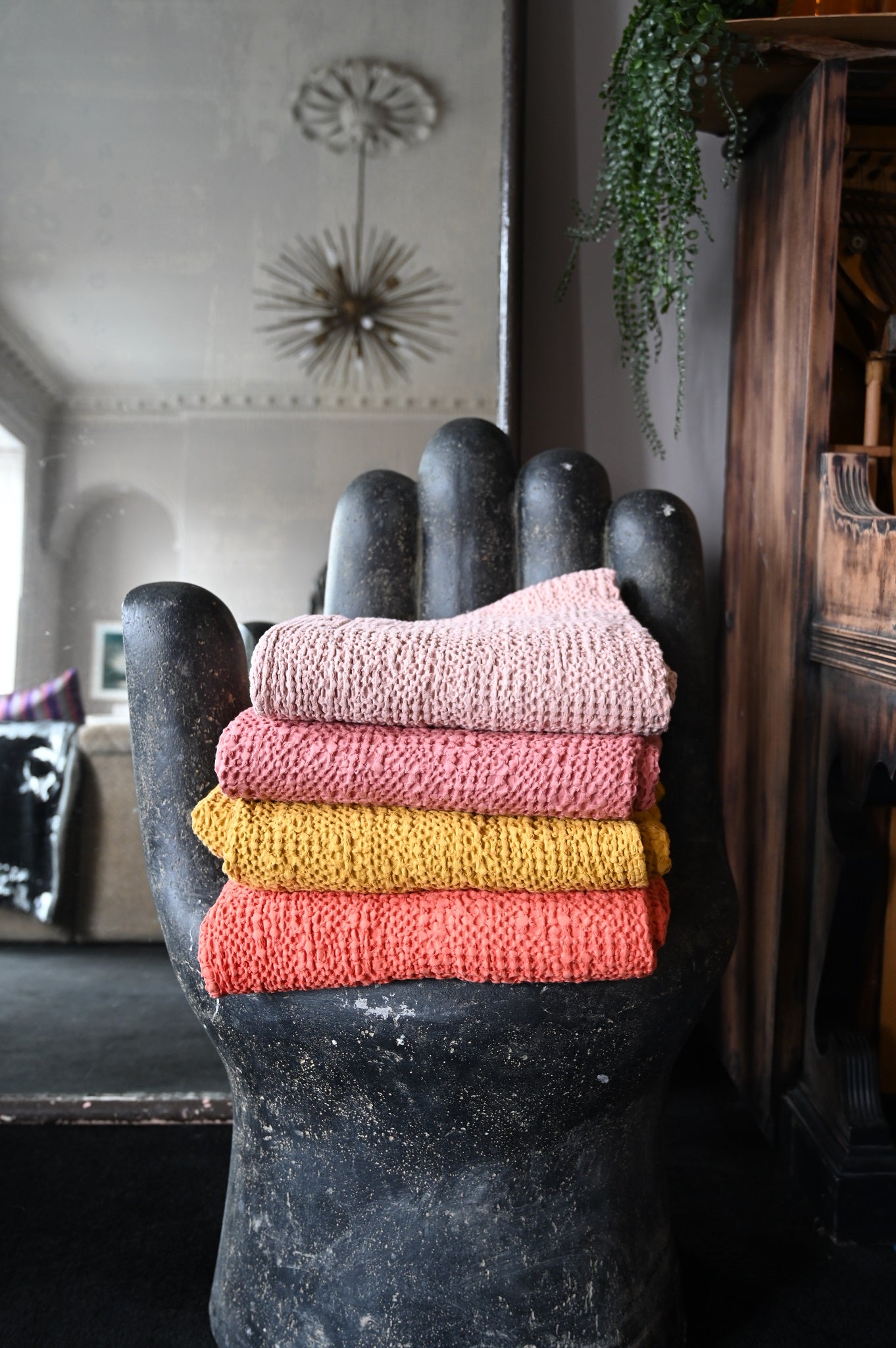 Stack of stonewashed cotton waffle throws in warm pink, coral, and mustard colours.