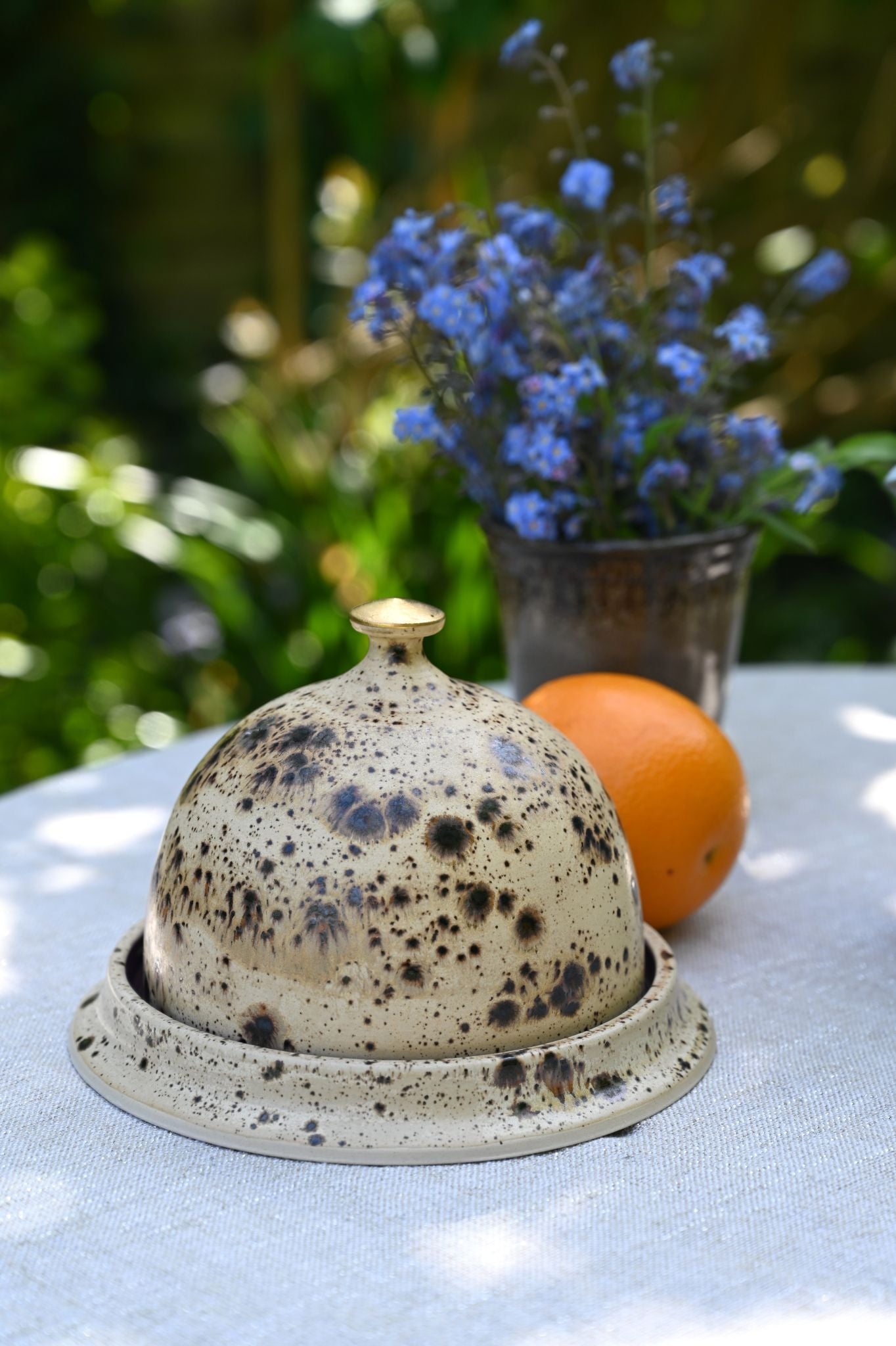Handmade speckled ceramic butter dish set with domed lid and gold metallic knob.