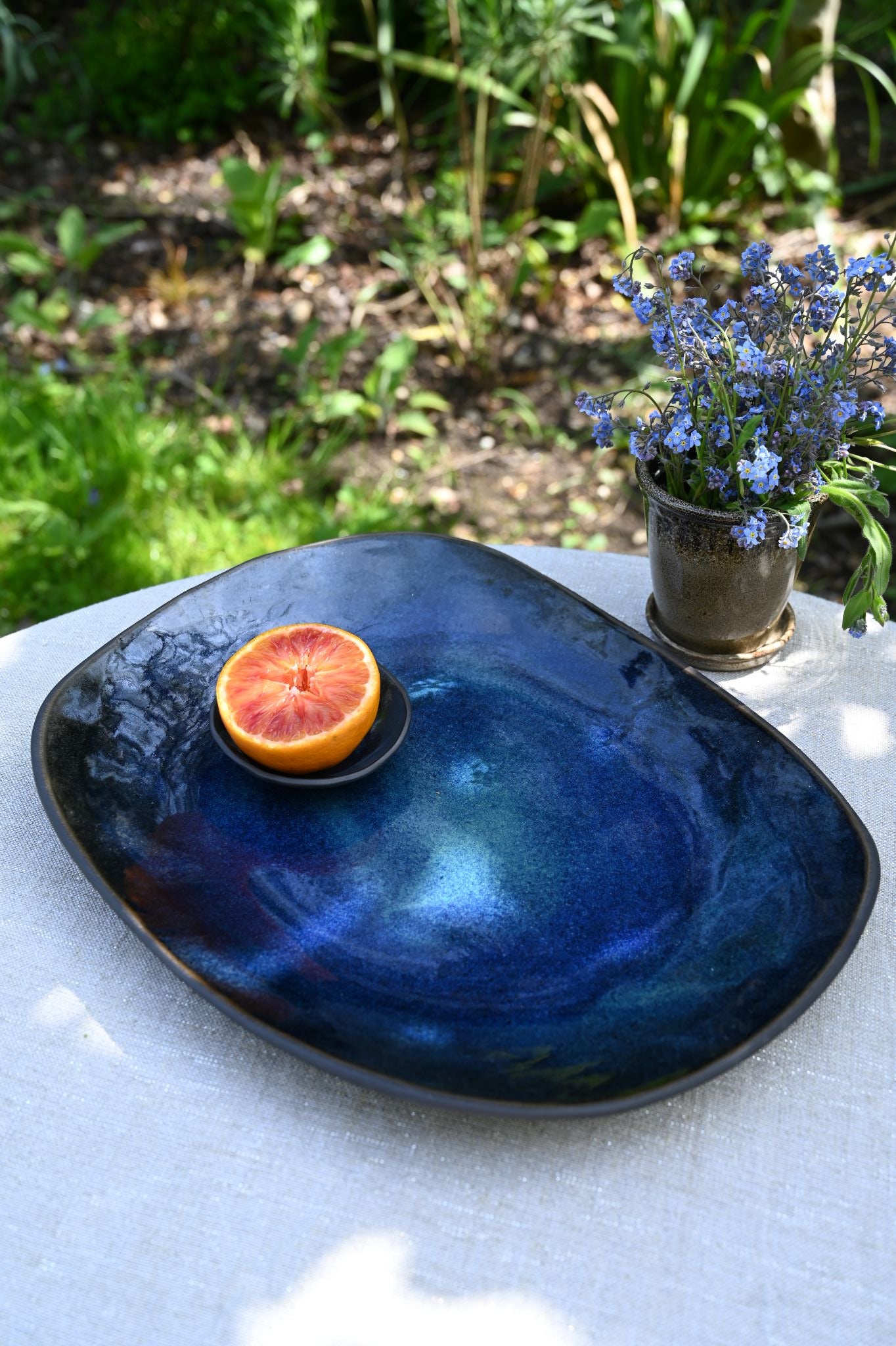 Large Hana Karim jade blue stoneware platter with organic shape and glossy glaze.