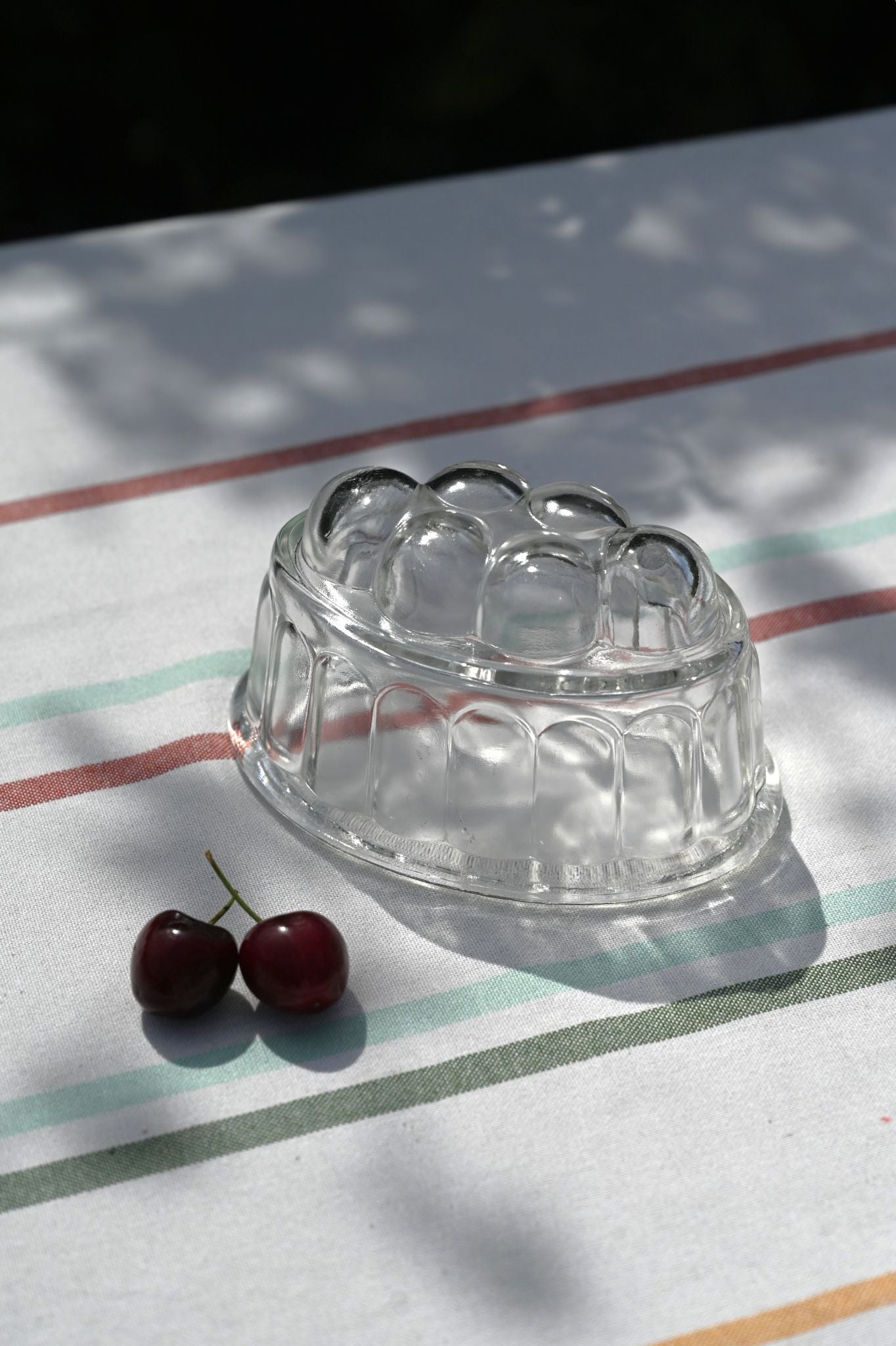 Vintage clear glass jelly mould with ribbed sides and domed bubble pattern, styled with cherries.