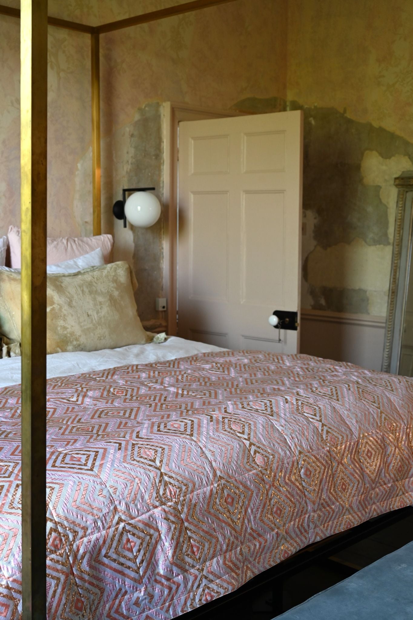 Luxurious pink and metallic gold geometric quilted bed throw on a four-poster bed.