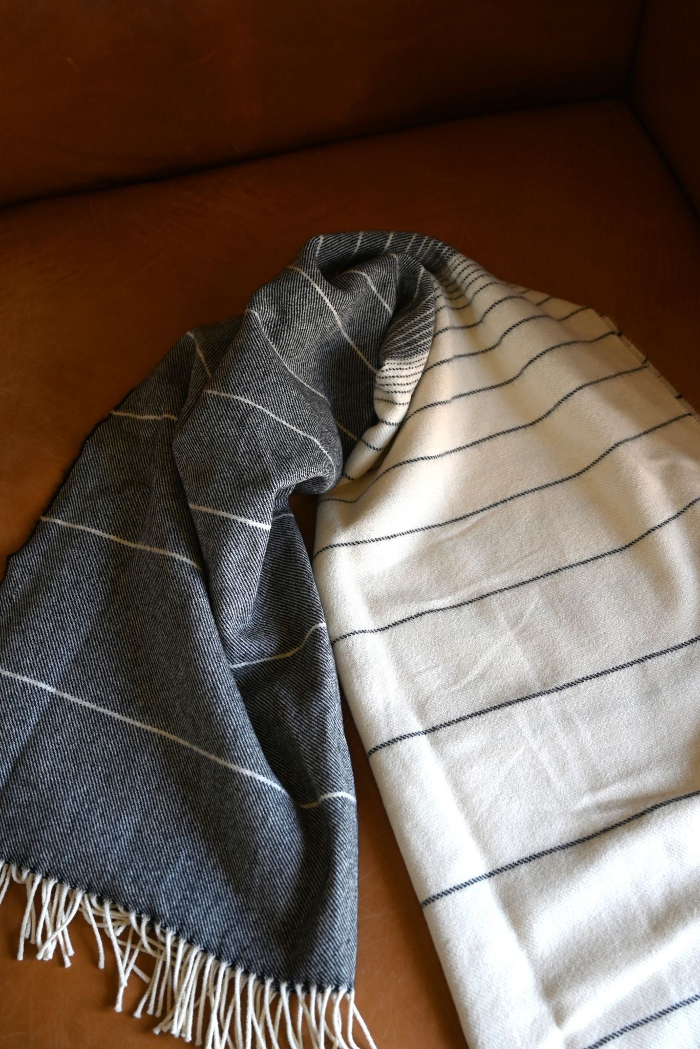 a striped blanket, one blue and one white, draped over a brown surface.