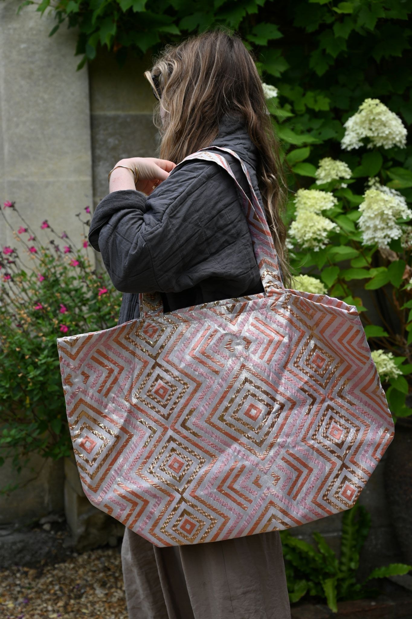 Person holding a patterned bag in a garden setting