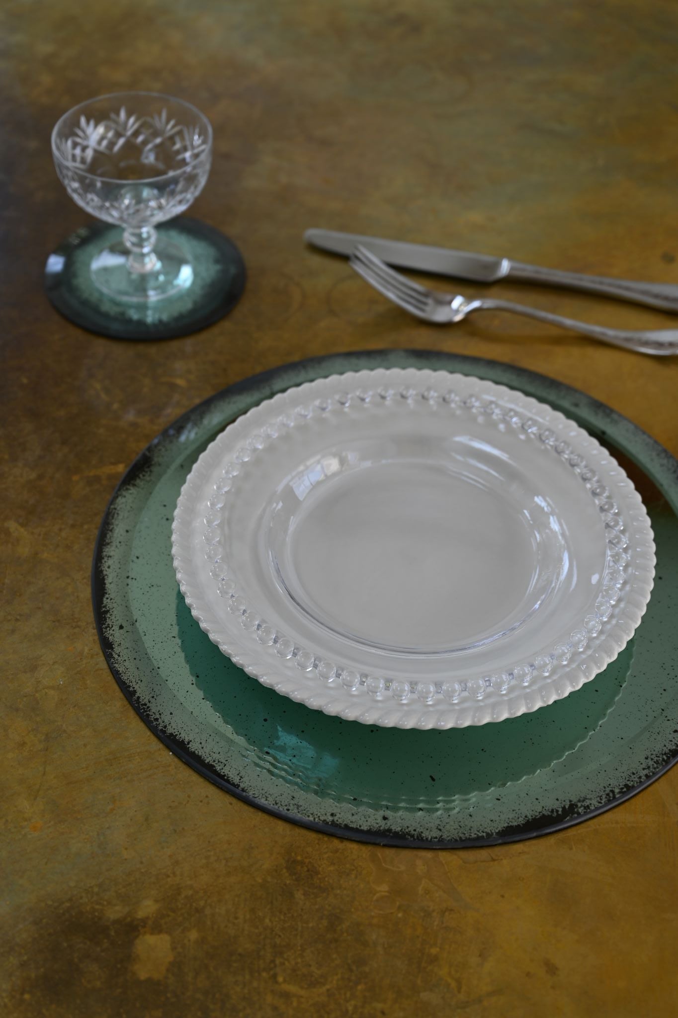 Circular hand-gilded mirror placemat with bevelled edge used as a table setting base.