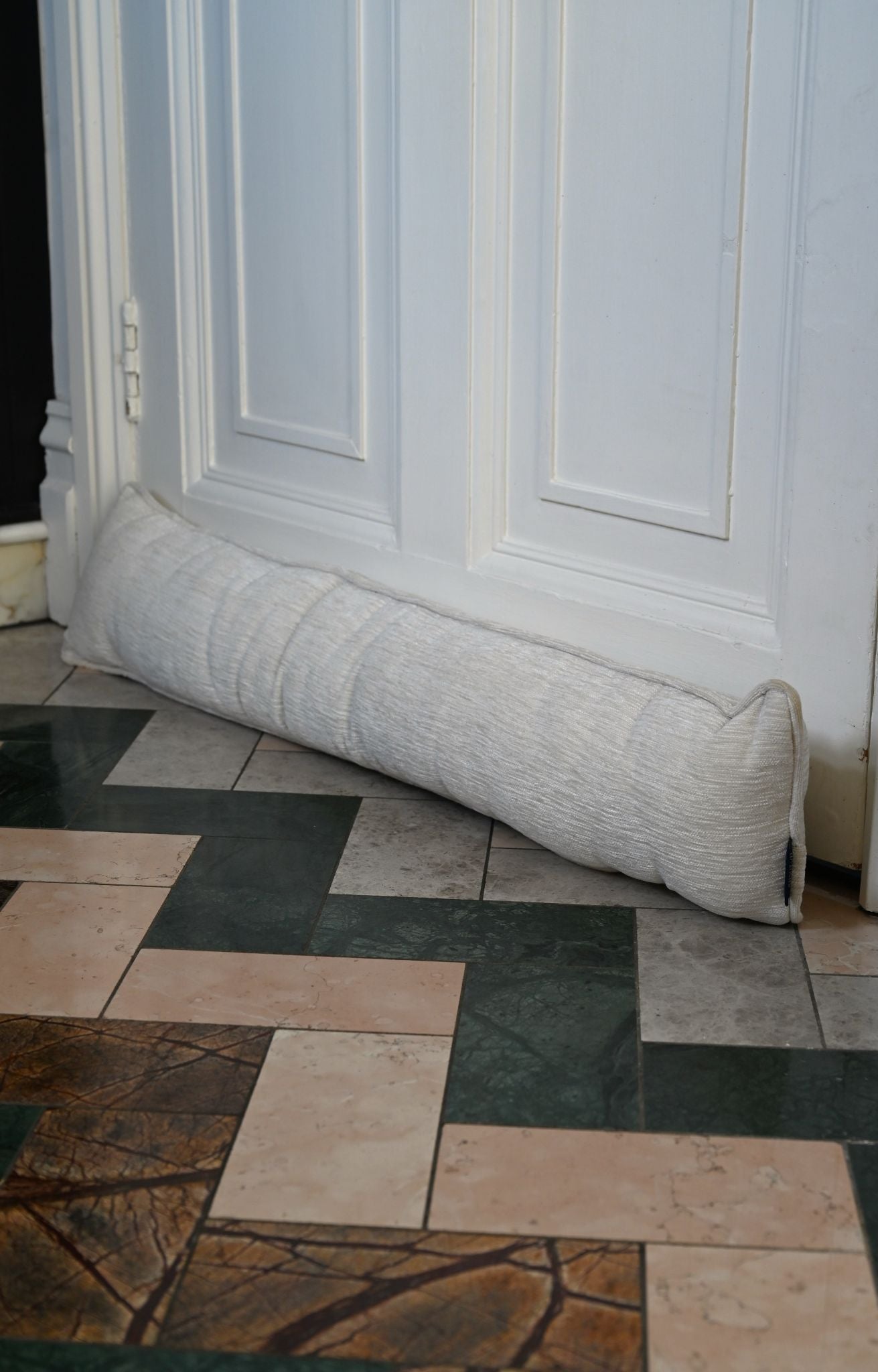 Ivory ribbed chenille draught excluder placed snugly against a white interior door.