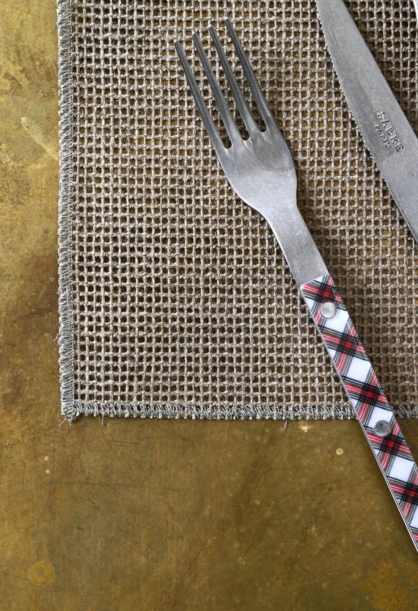 Woven linen placemats featuring metallic gold, silver, and copper stitched borders.