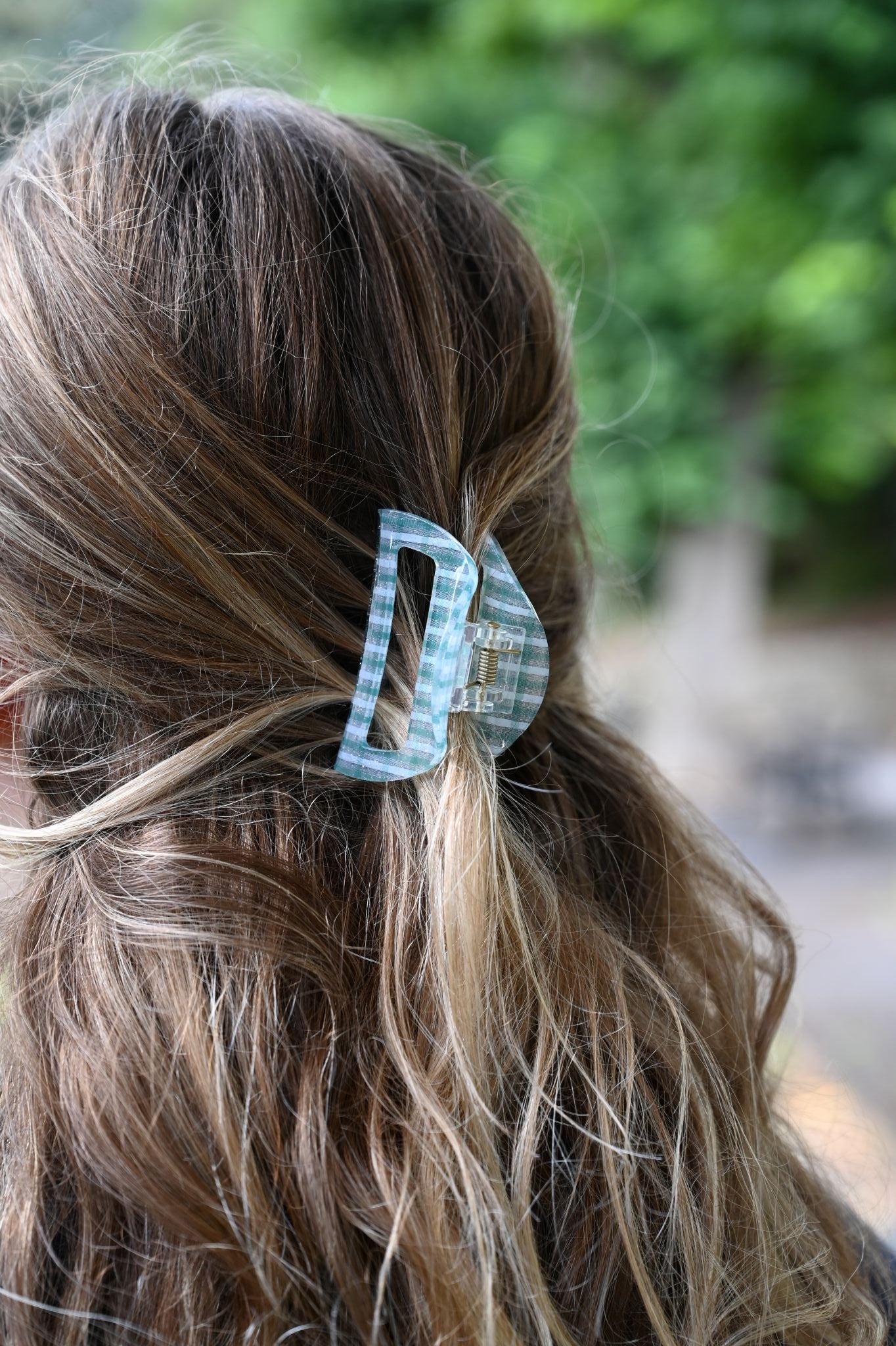 Close-up of a hair clip in a person's hair with a blurred green background