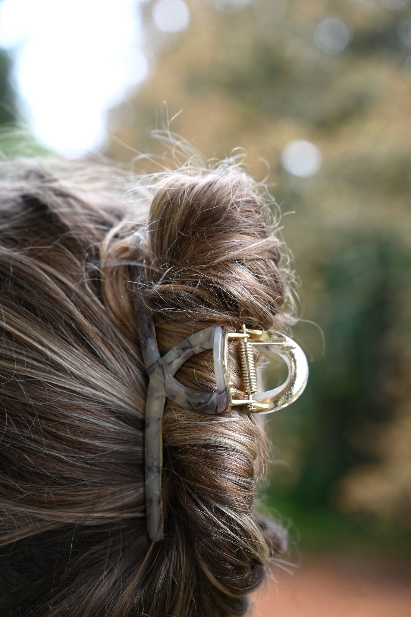Close-up of a hair clip in a person's hair with a blurred natural background