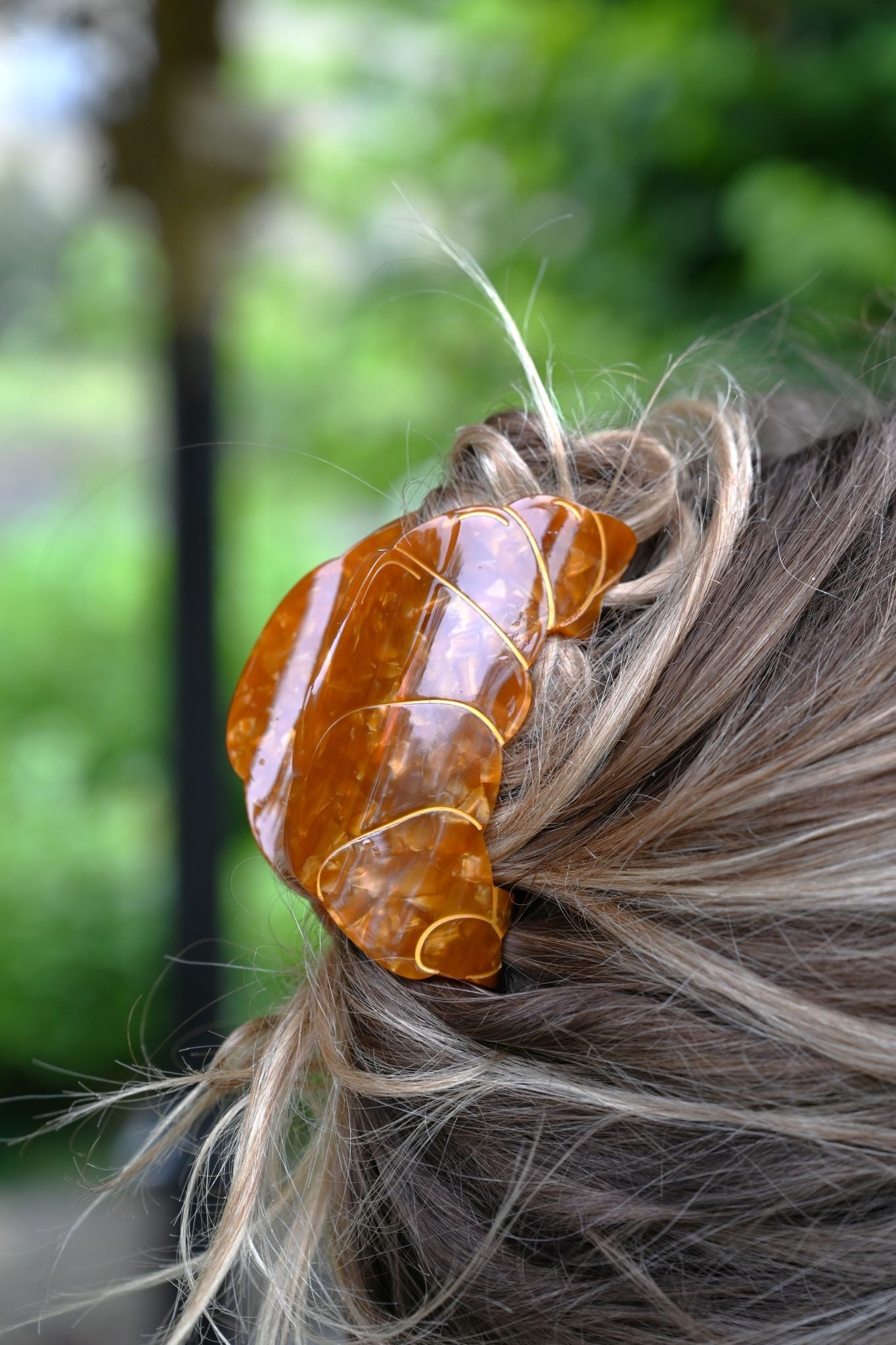 Close-up of a hair clip with a decorative stone in a blurred outdoor setting