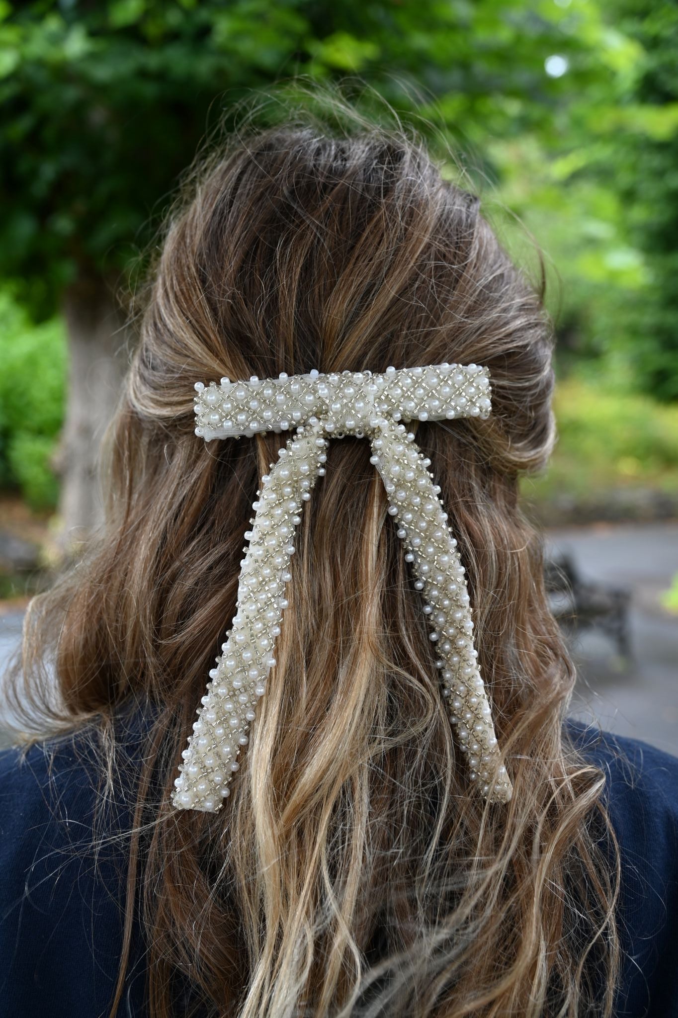 Large white pearl and seed bead embellished hair bow clip securing a half-up style.