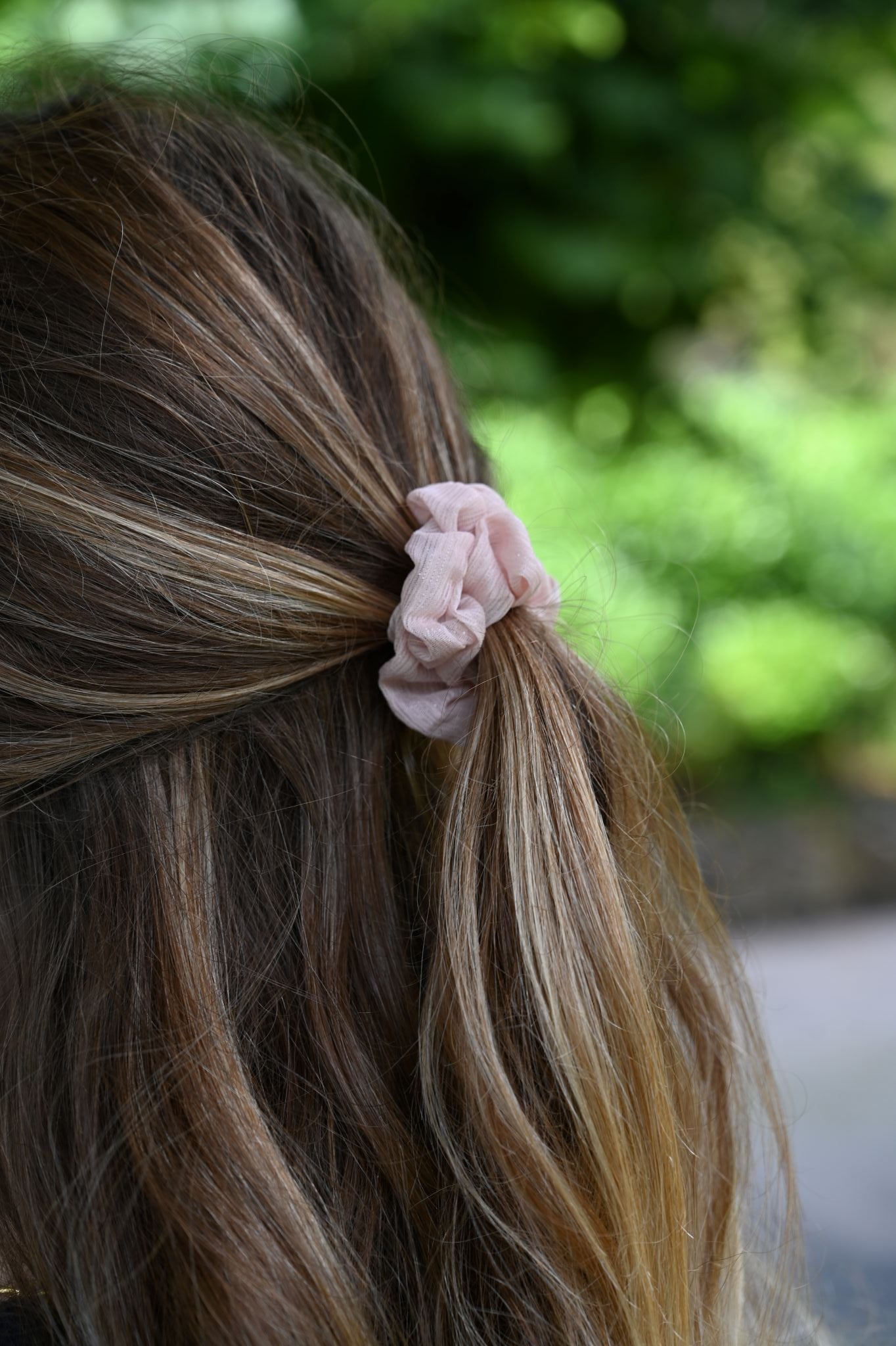 Close-up of a hair tie in a person's hair with a blurred green background