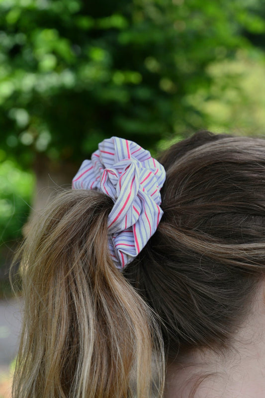 Multicolored scrunchie on a ponytail with a blurred green outdoor background