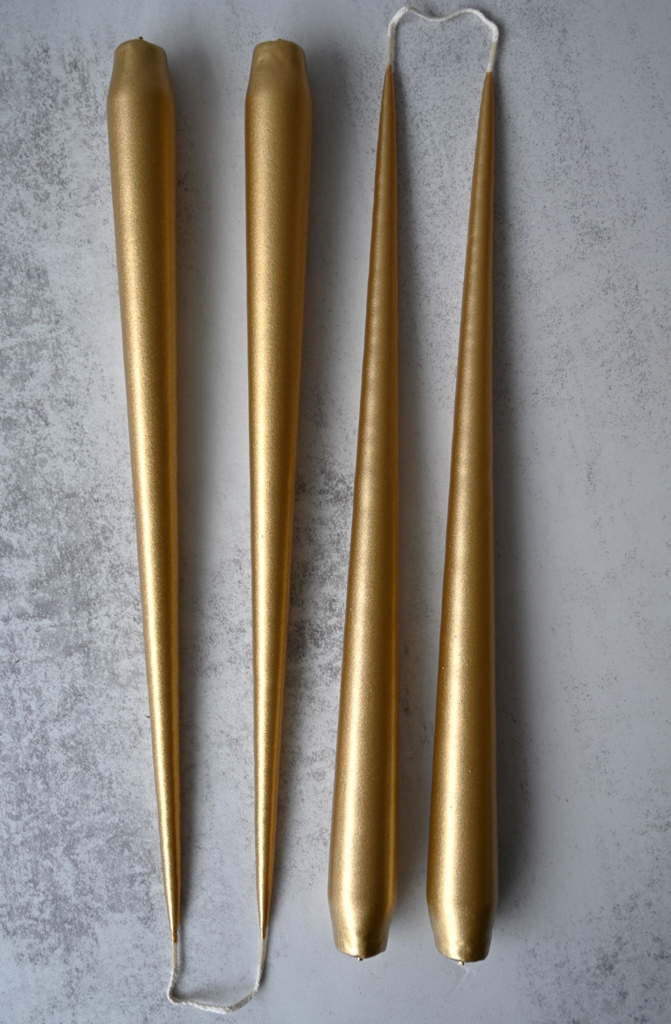 Set of four long, slender metallic gold taper candles for elegant dining.