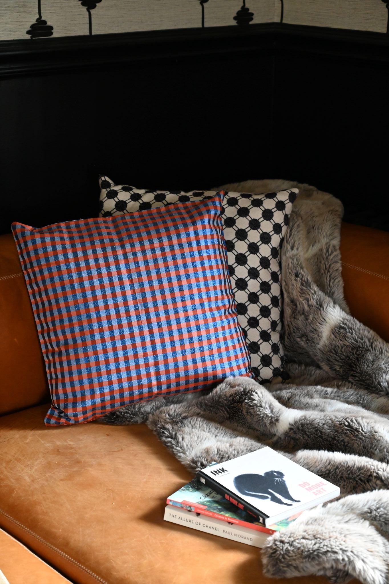 Navy and orange sparkly gingham cushion styled on a distressed leather sofa.