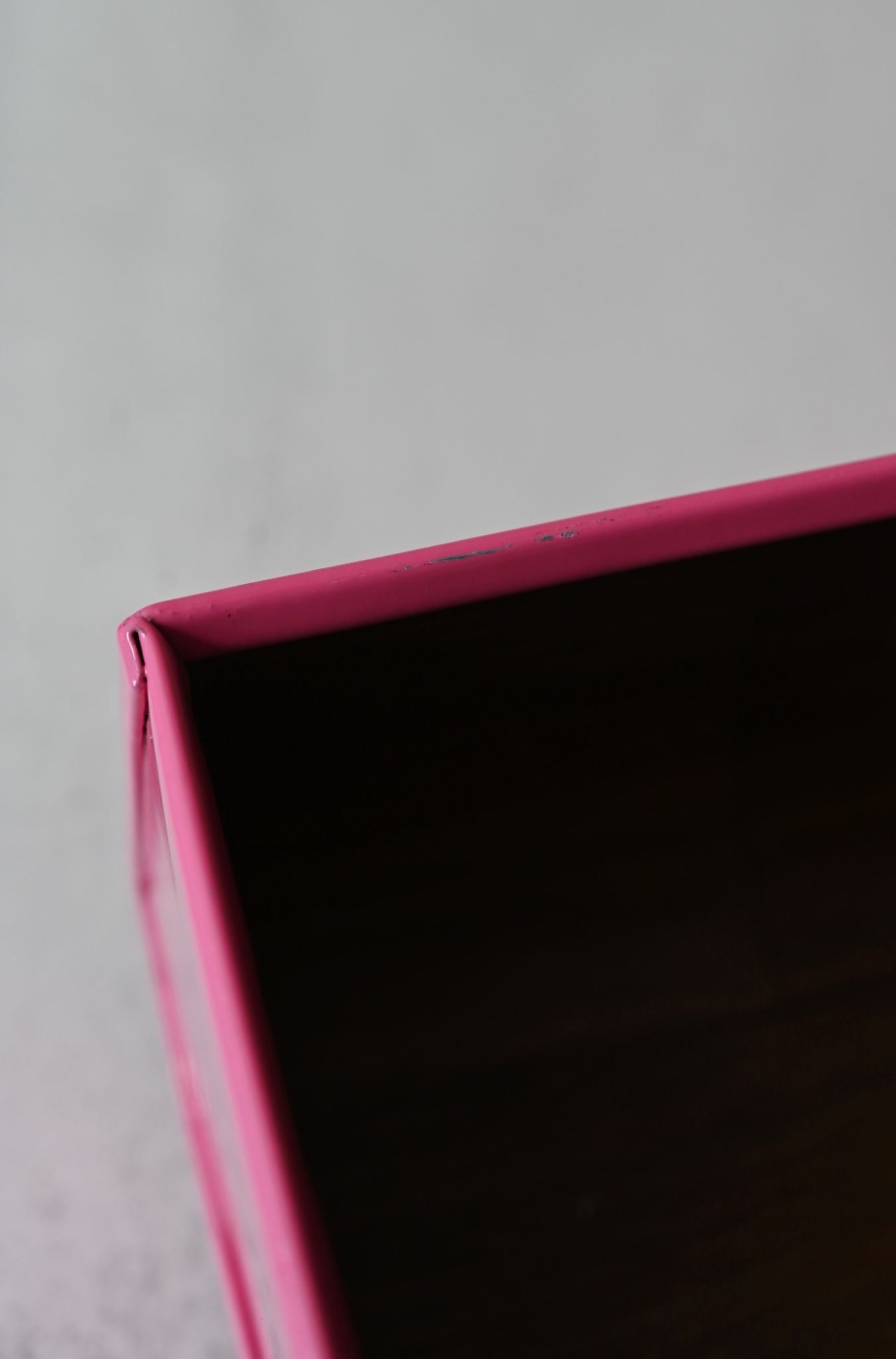 Close-up of a pink tray corner on a gray background. Slight scuffs visible