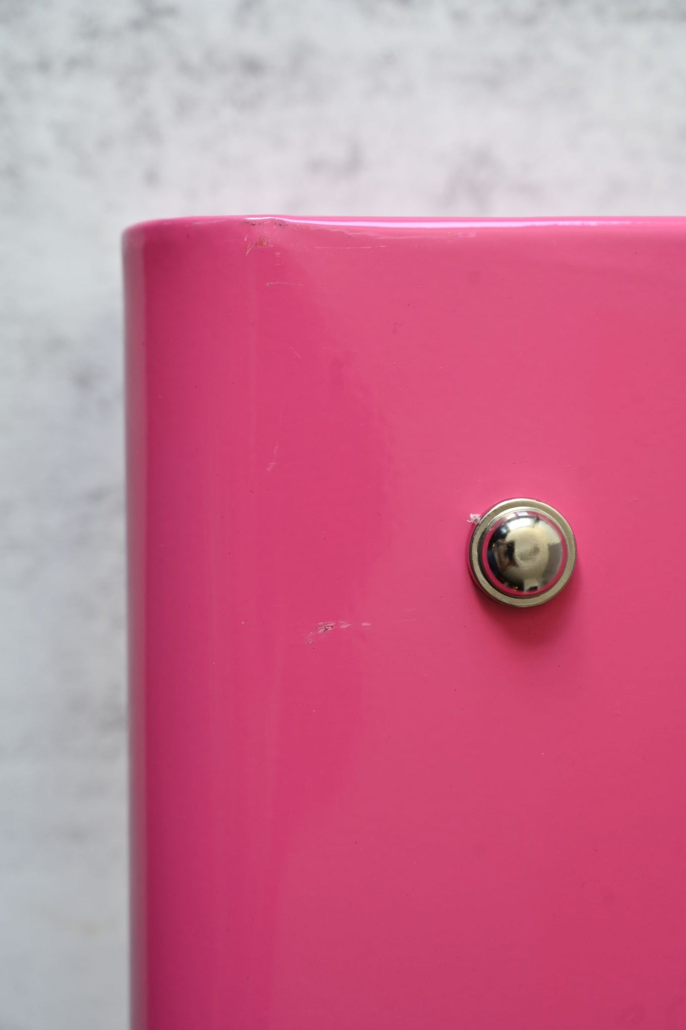 Close-up of a pink tray corner with a slight scratch on a light gray background