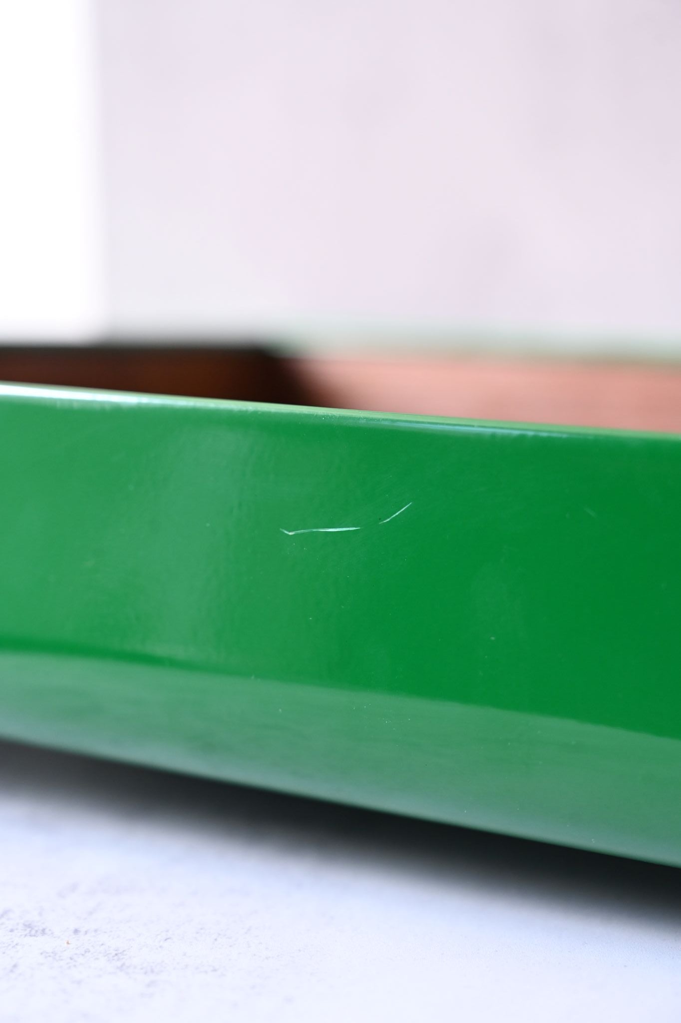 Close-up of a green tray, with scratches on a blurred background