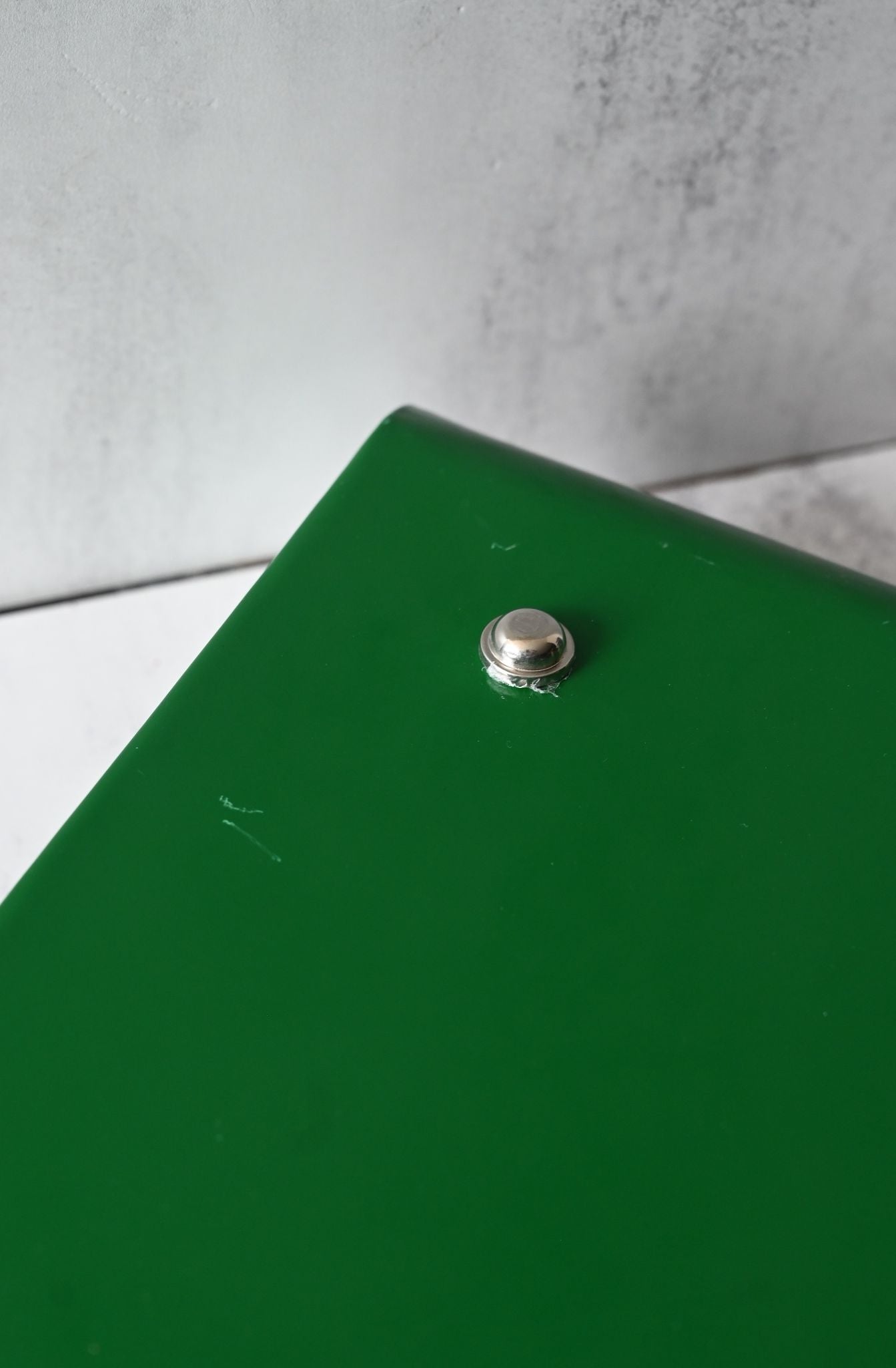 Close-up of a scratched green tray on a light gray background