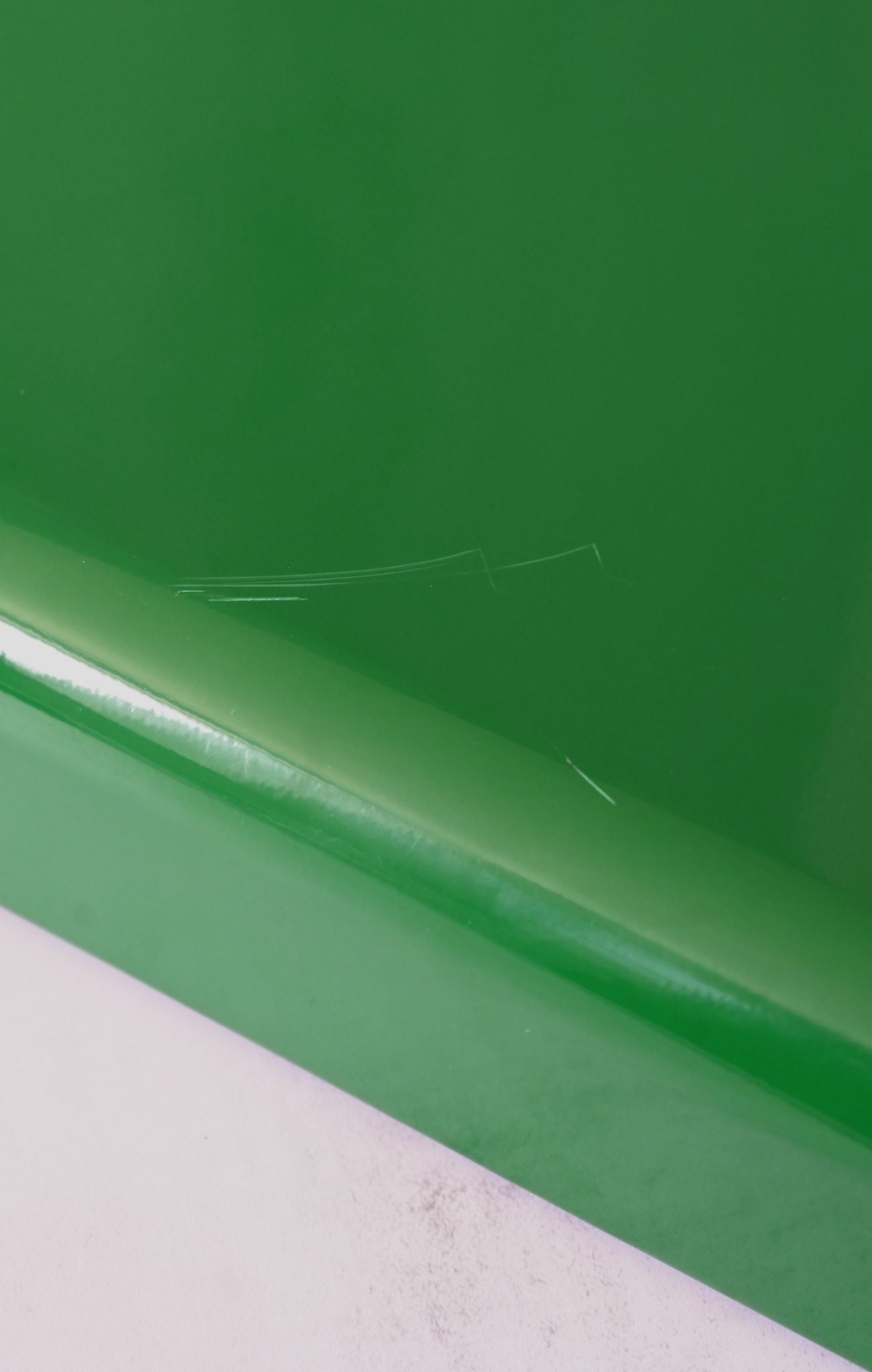 Close-up of a green tray, showing small scratches, on a white background
