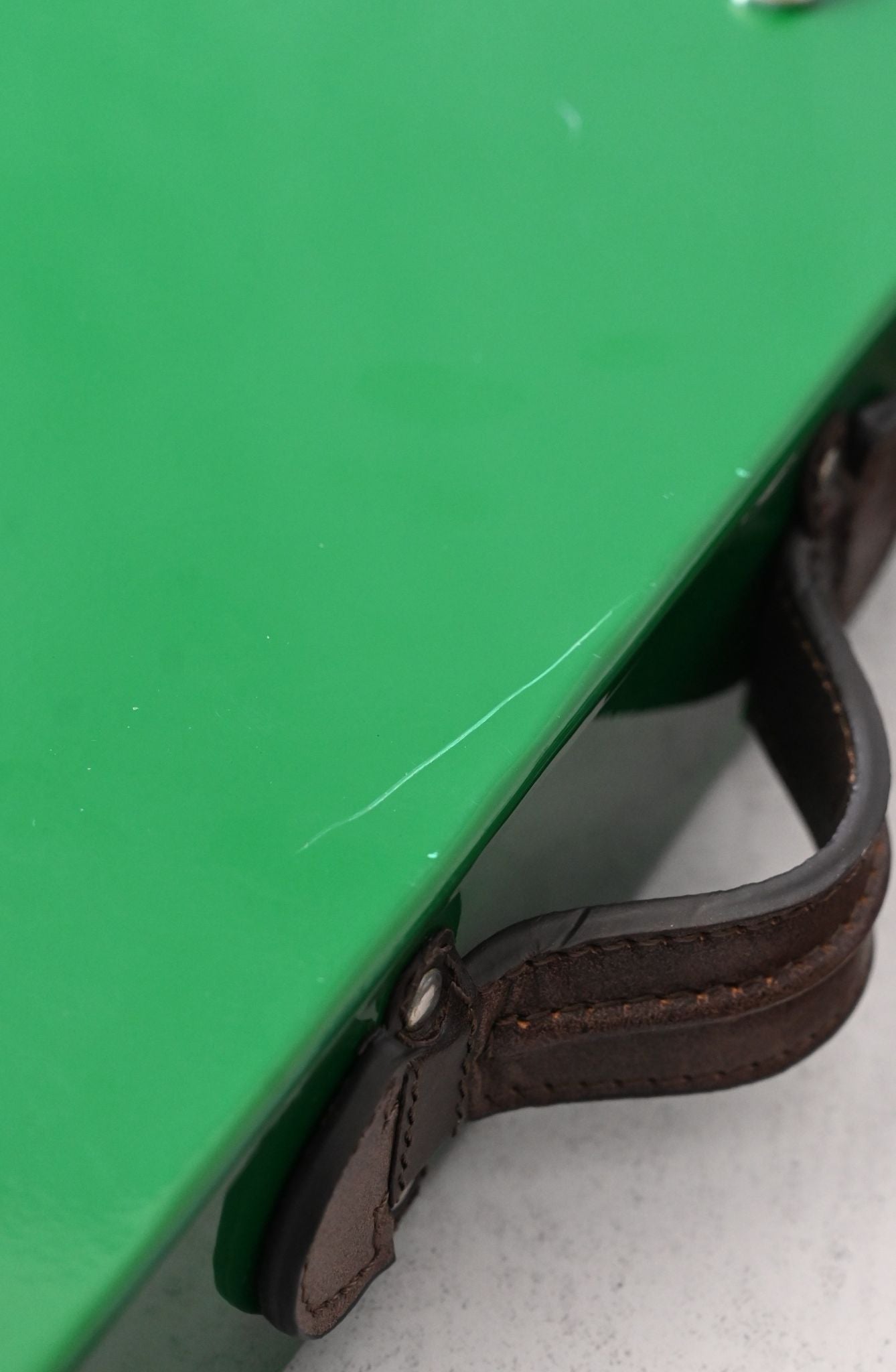 Brown leather strap attached to a green metal tray, slight scratches