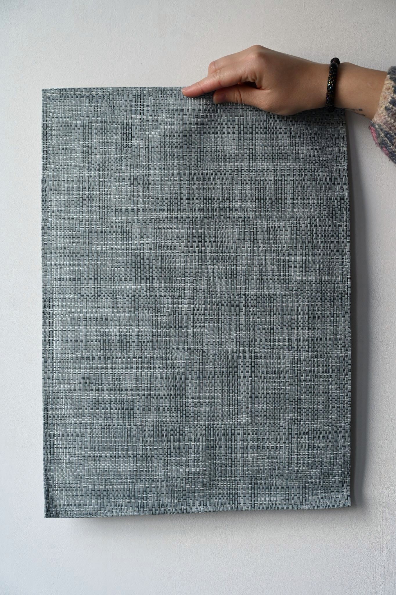 Person holding a blue woven placement against a white background