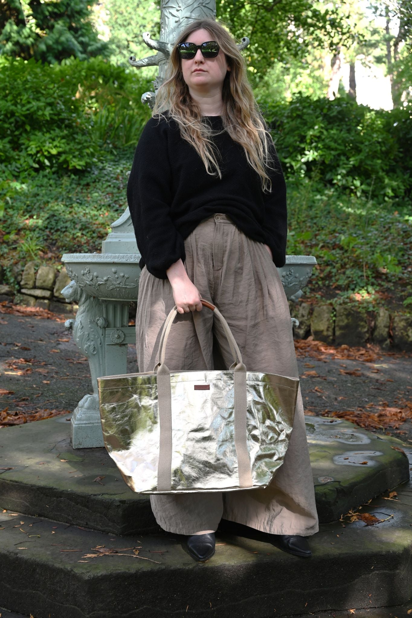 Woman holding a pale gold tote bag in an outdoor setting