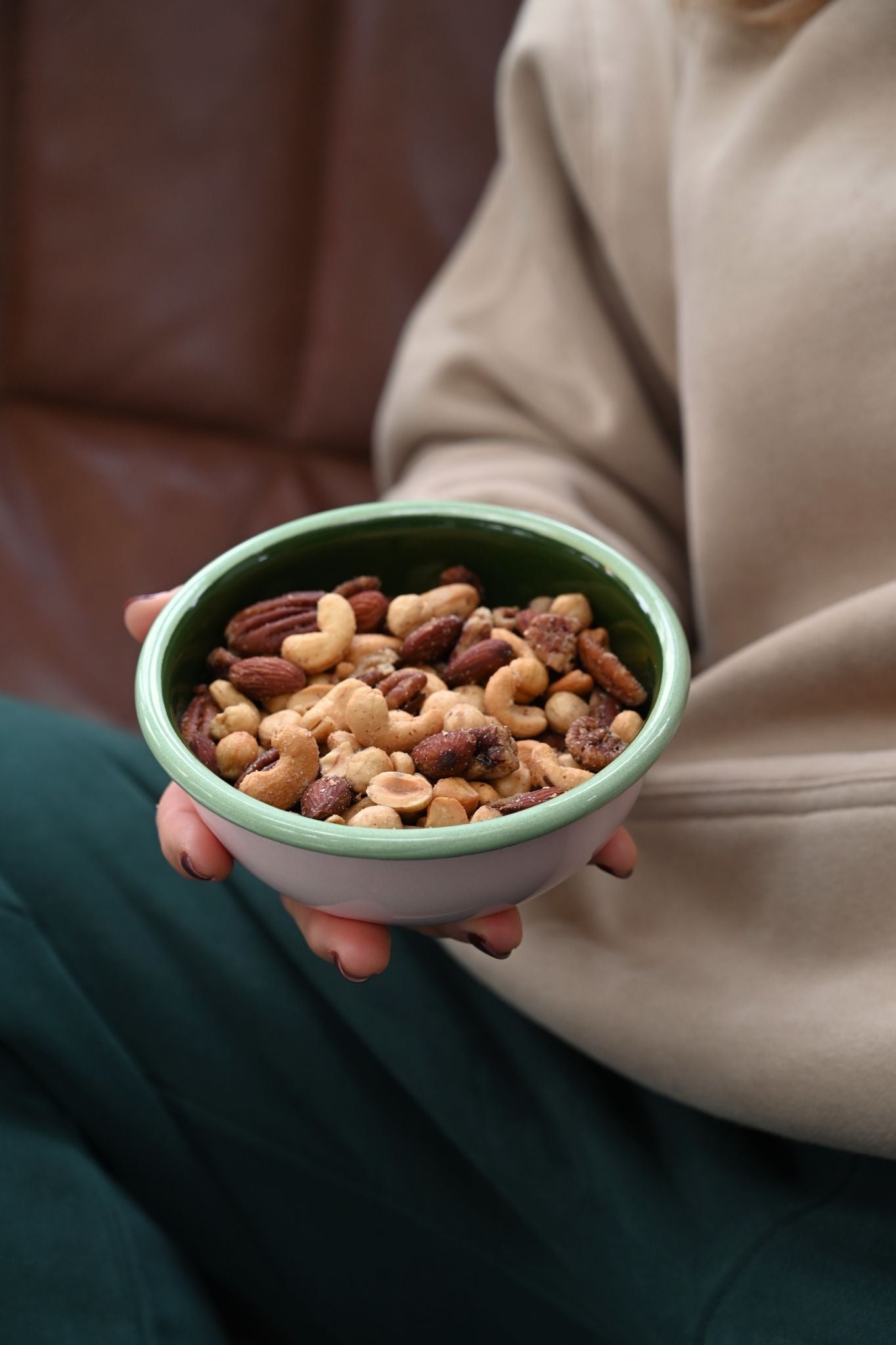 Small tricolour pink and green enamel snack bowl filled with mixed nuts.