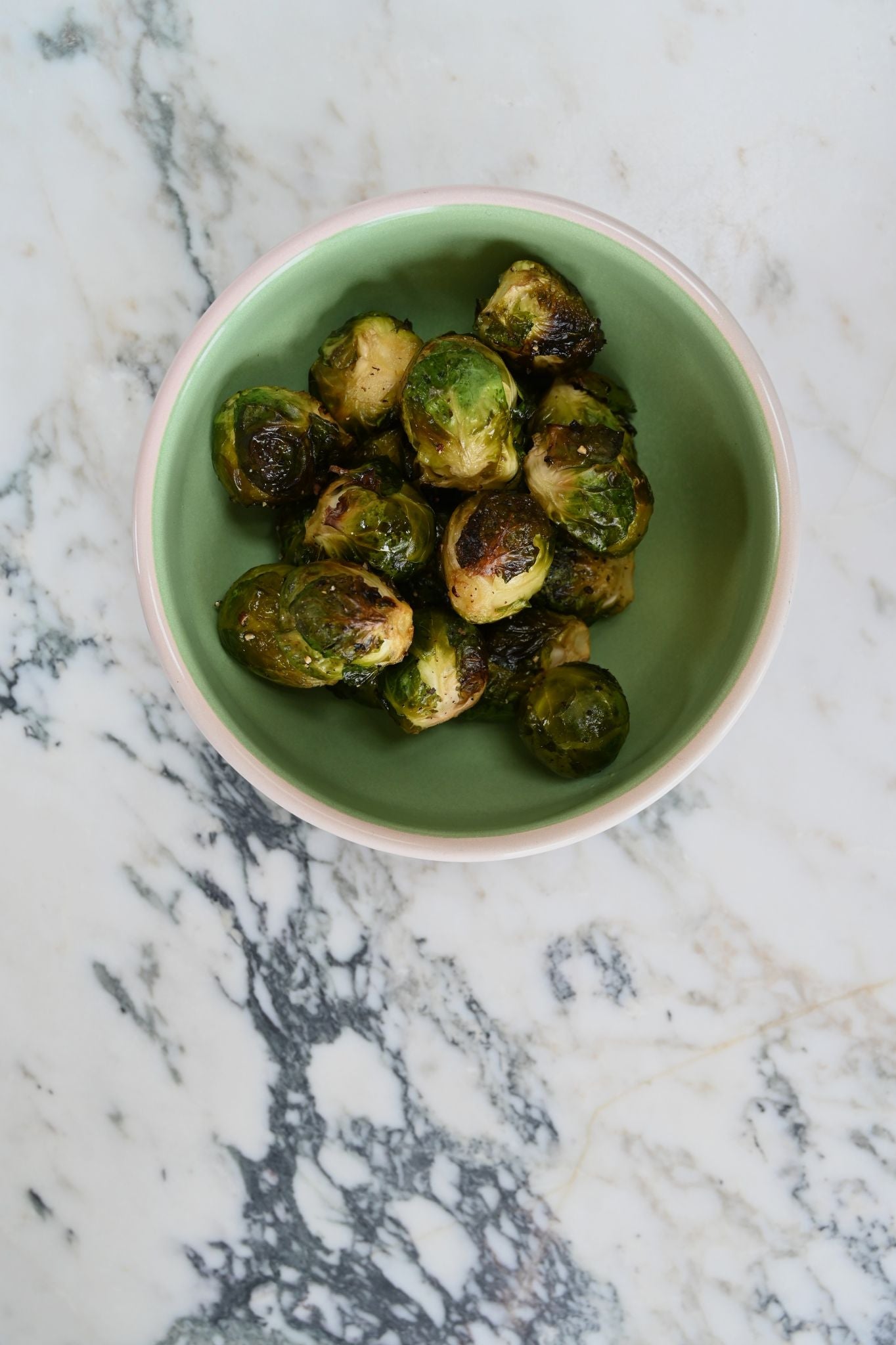 enamel cereal bowl with roasted Brussels sprouts on a marble surface