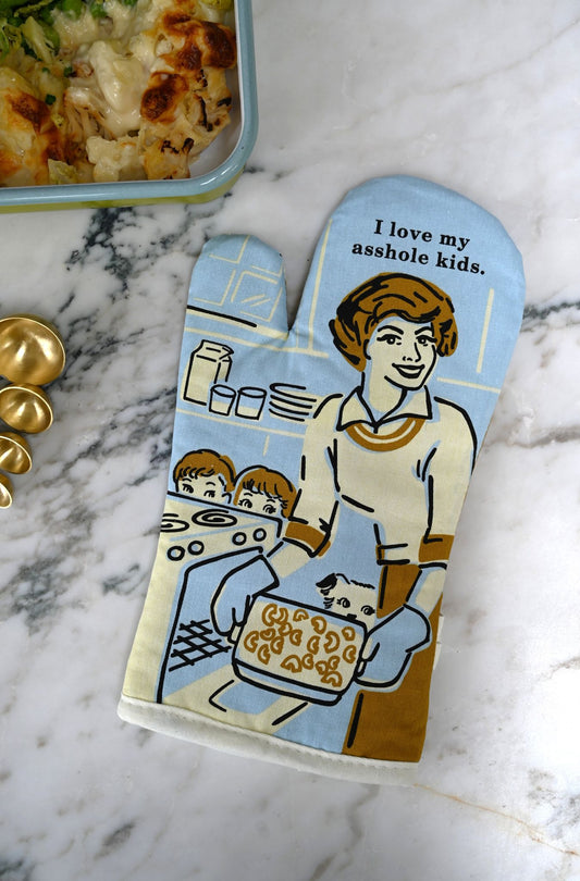 Oven mitt with a humorous design and 'I love my asshole kids' on a marble surface