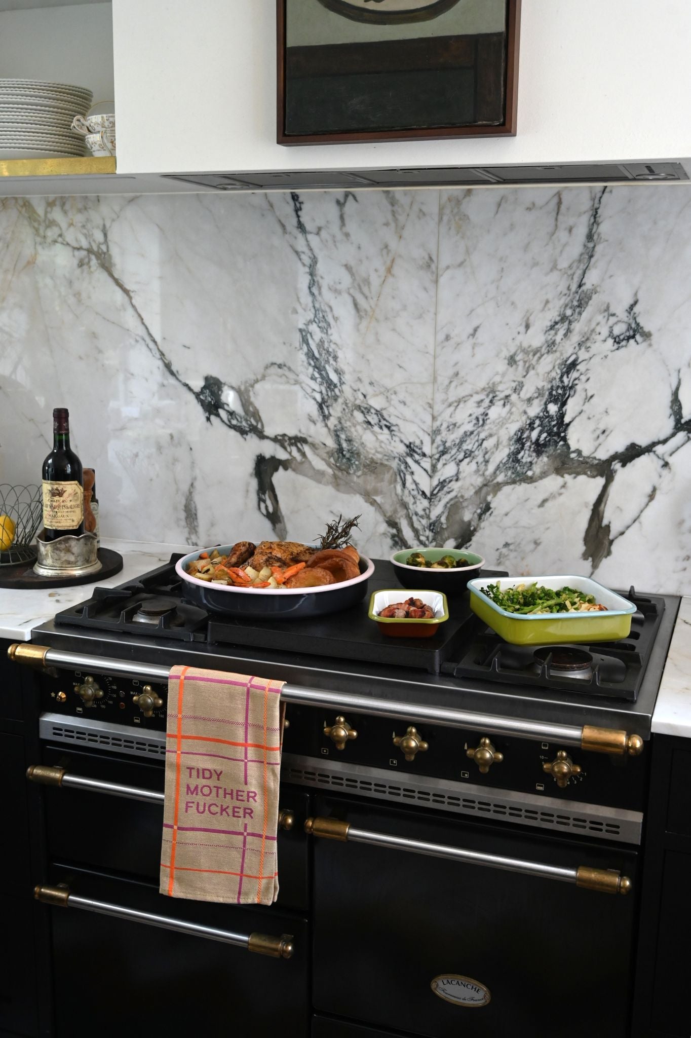 Modern kitchen with black stove and selection of Always Sunday enamelware filled with food against a marble backsplash