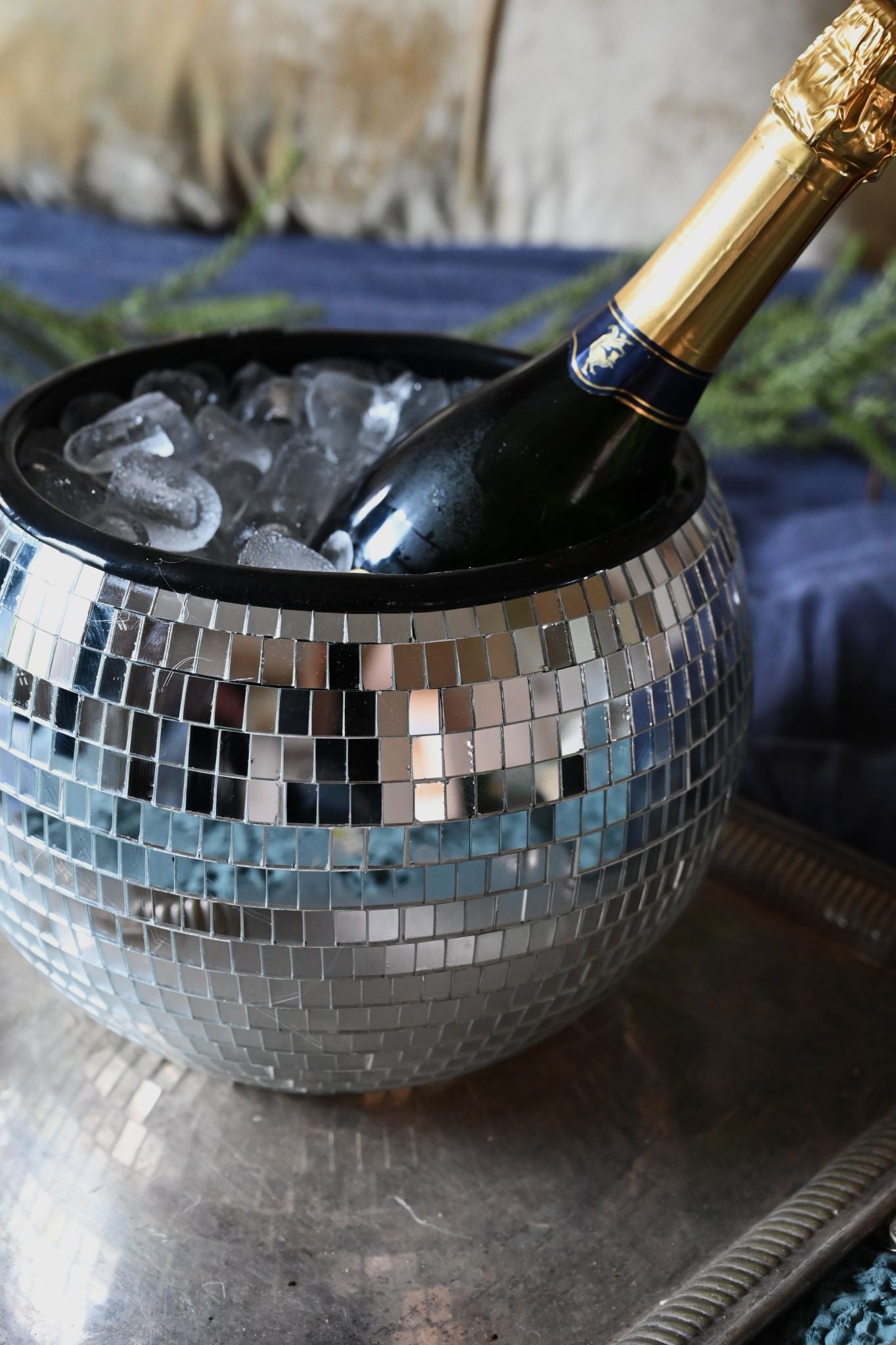 Bottle of champagne in a disco ball ice bucket with ice cubes