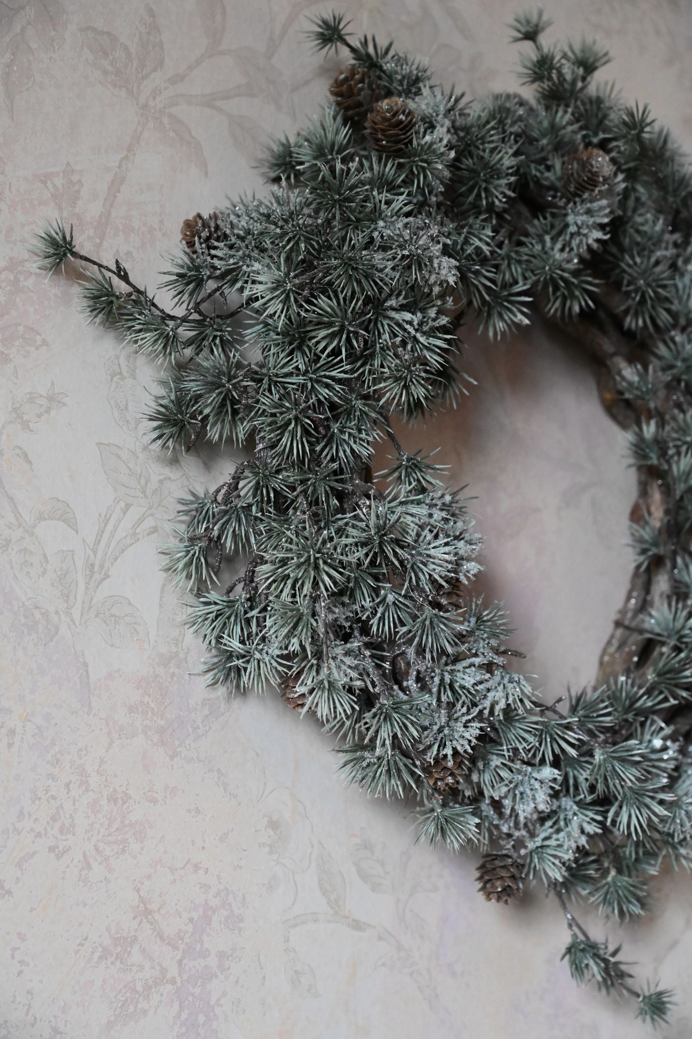 Frosted wreath with pinecones on a textured surface