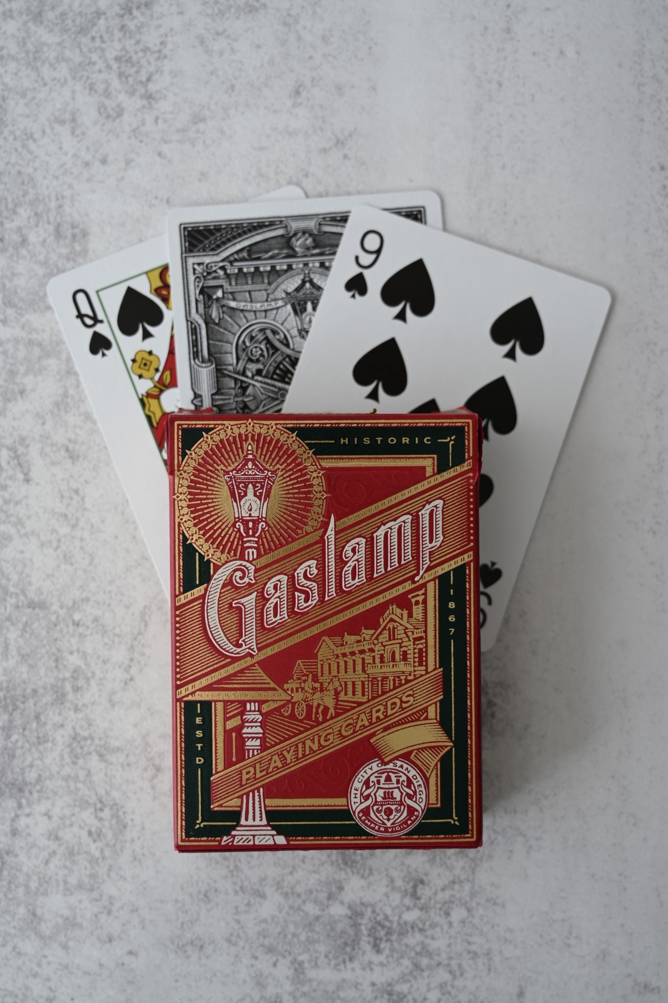 Crimson red Gaslamp Playing Cards tuck box with gold foil and fanned custom cards.