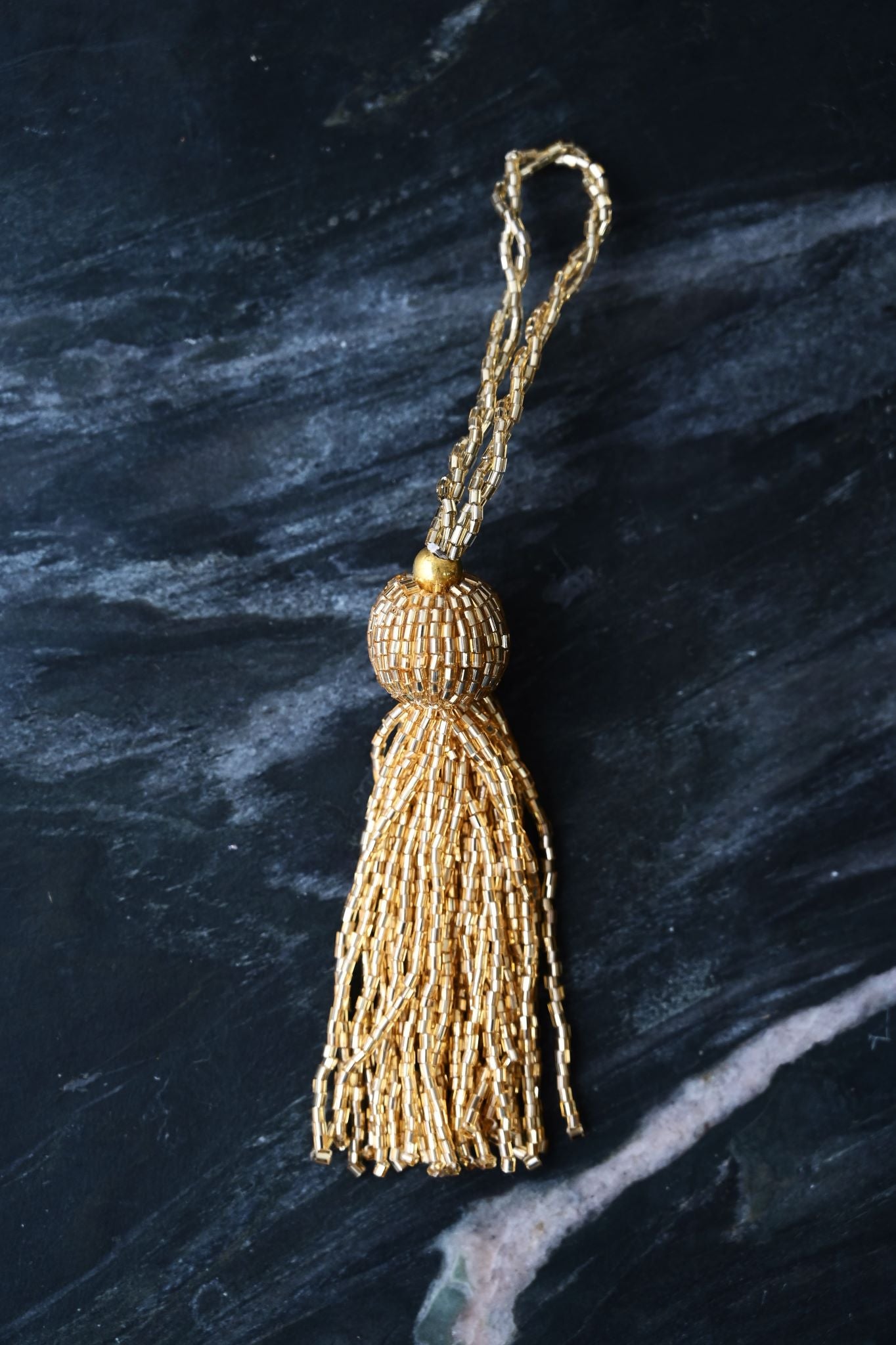 Luxurious Art Deco gold beaded tassel ornament with long flowing strands.