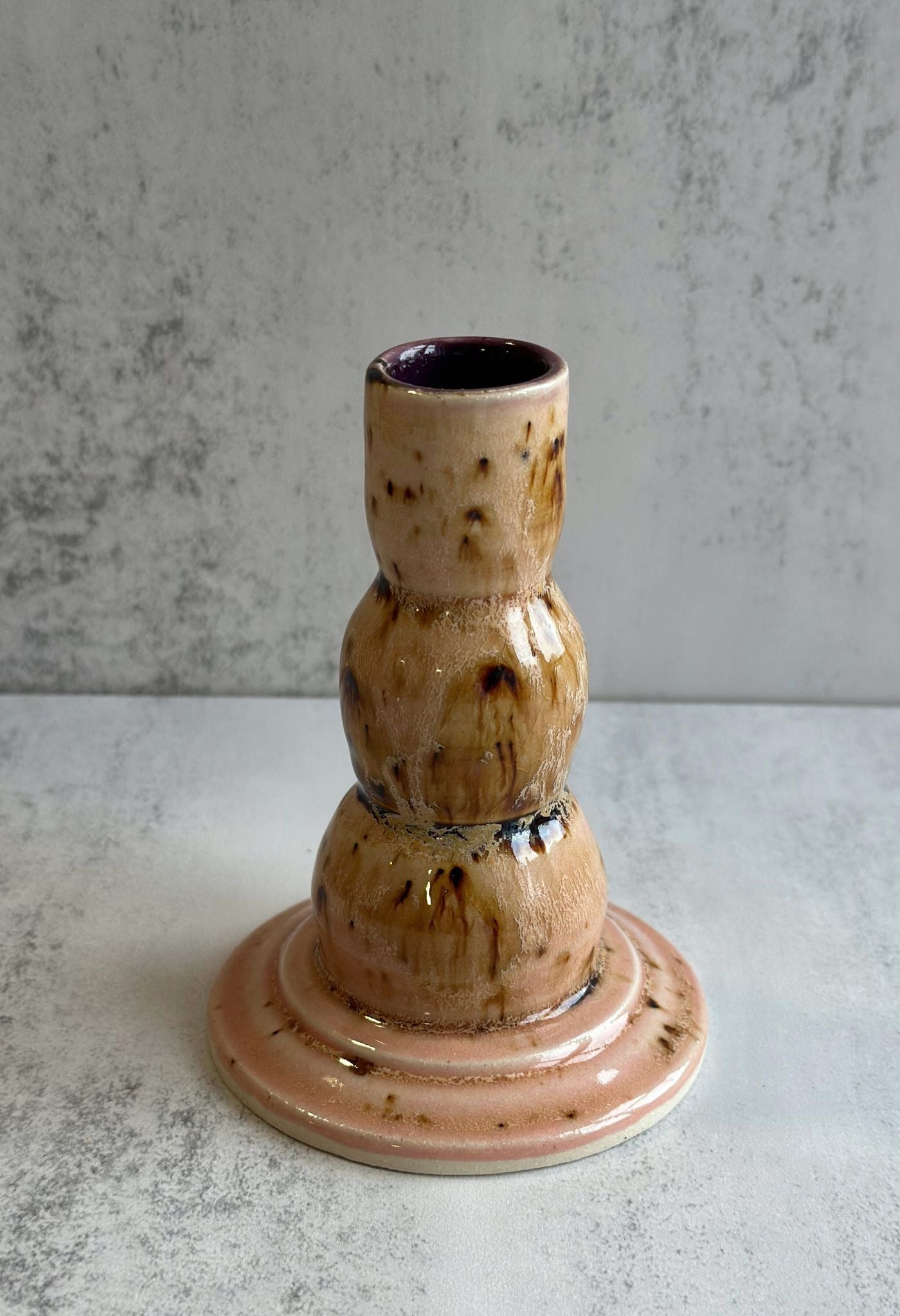 Tiered ceramic candle holder with pale pink and brown speckled reactive glaze.
