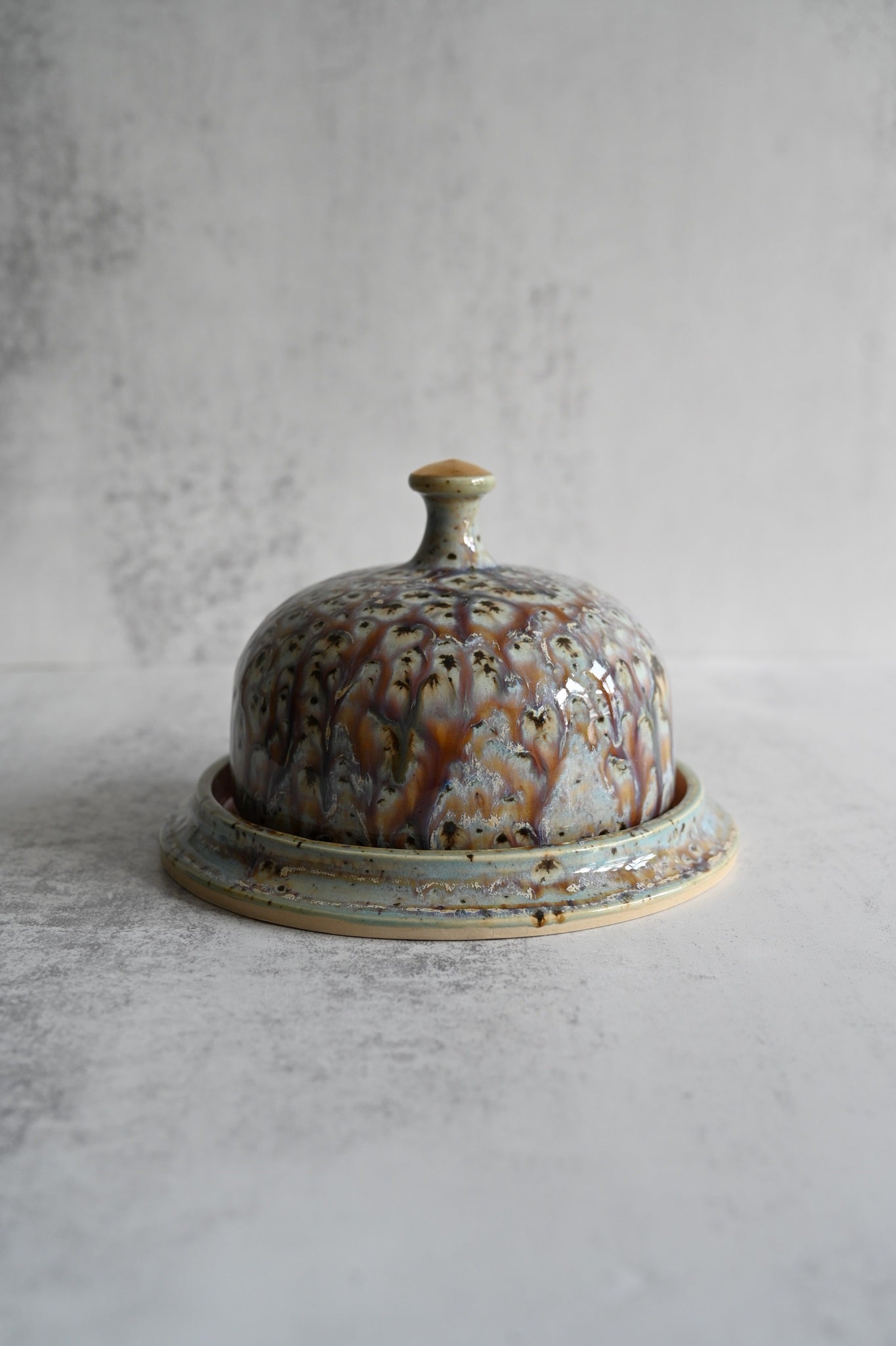 Handmade ceramic lidded butter dish in iridescent peacock blue glaze with gold knob.