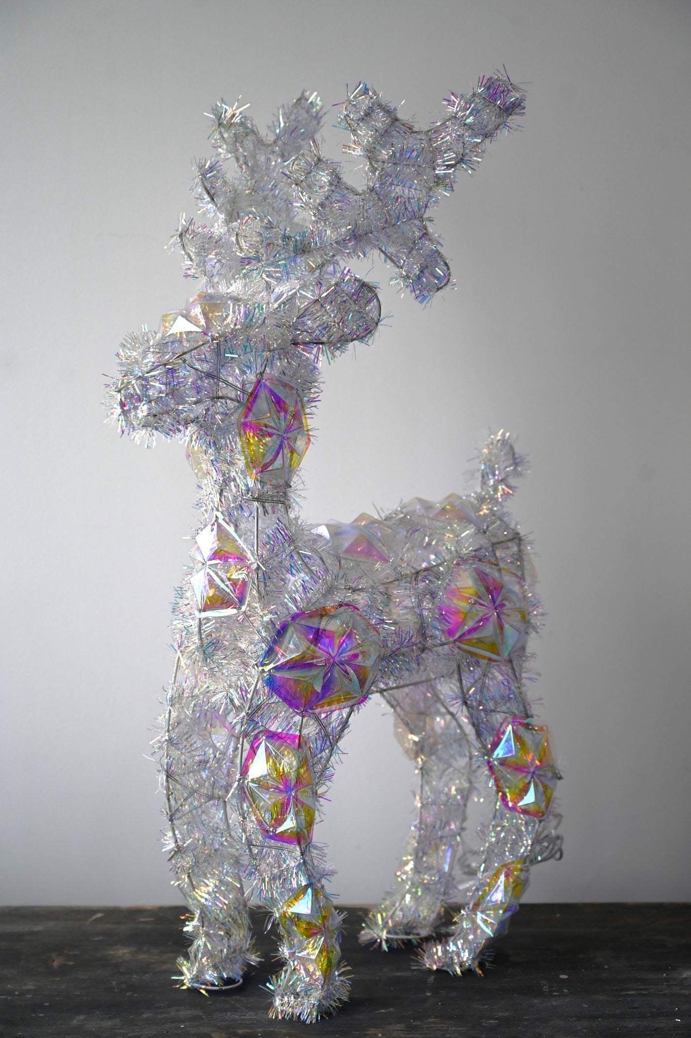 Large standing LED reindeer decoration made of silver tinsel and iridescent faceted acrylic.