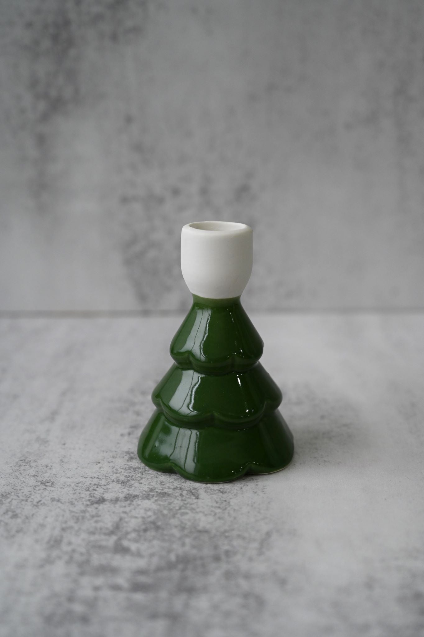 Three green and white glossy ceramic Christmas tree taper candle holders with textured details.