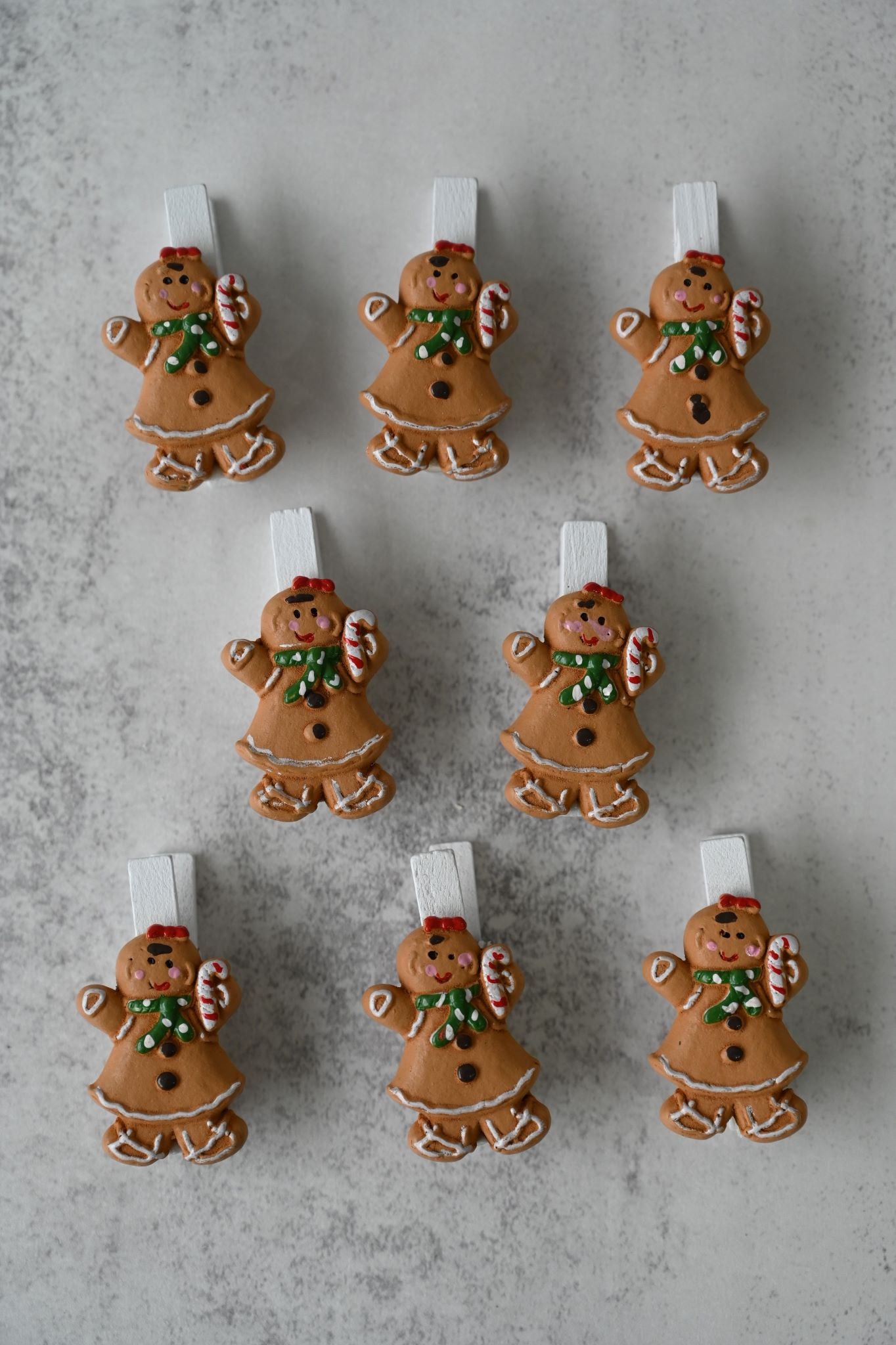 Set of eight wooden gingerbread girl clips with festive icing and candy canes.