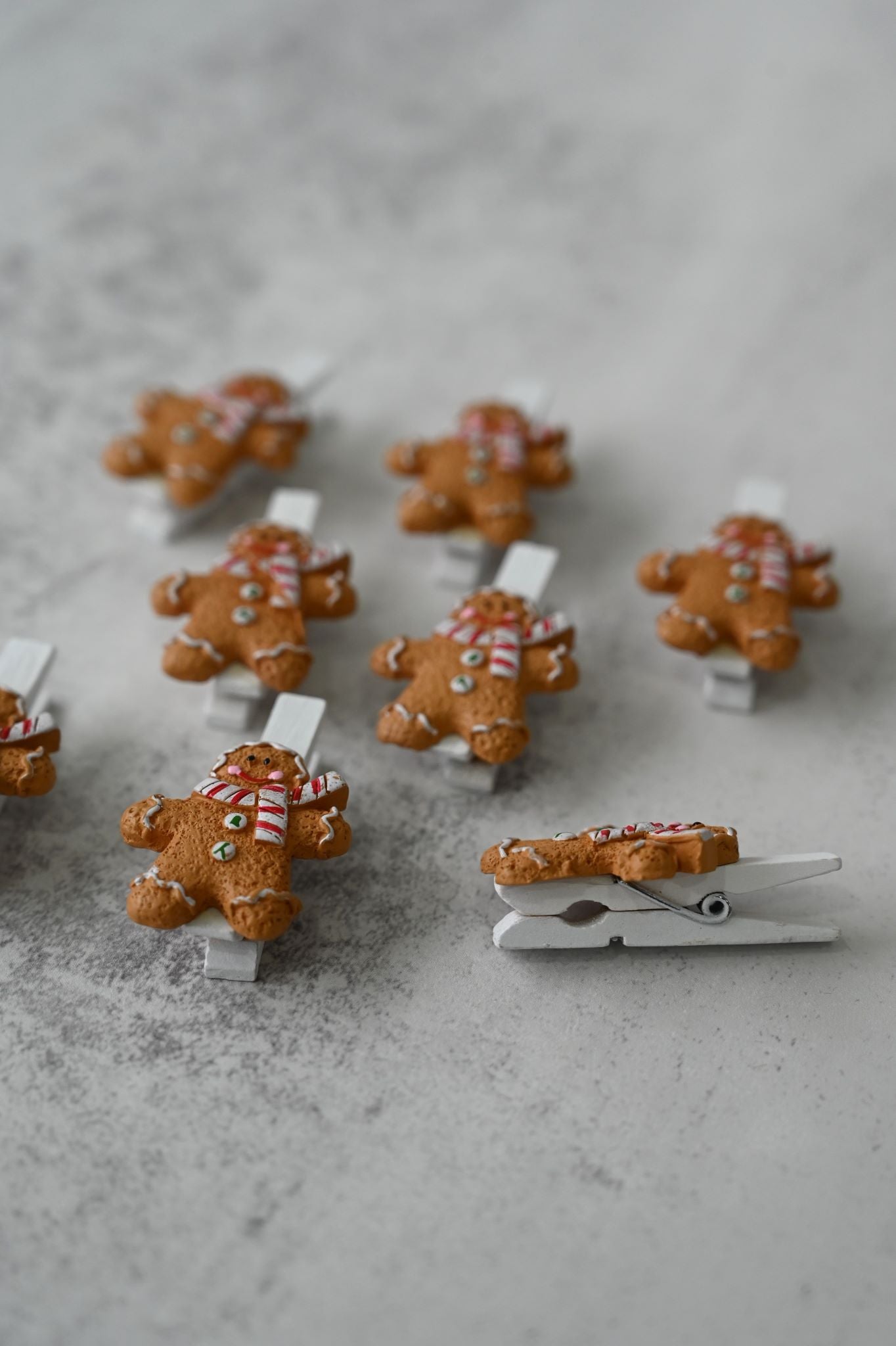 Set of eight festive gingerbread man figures on white wooden craft clips.