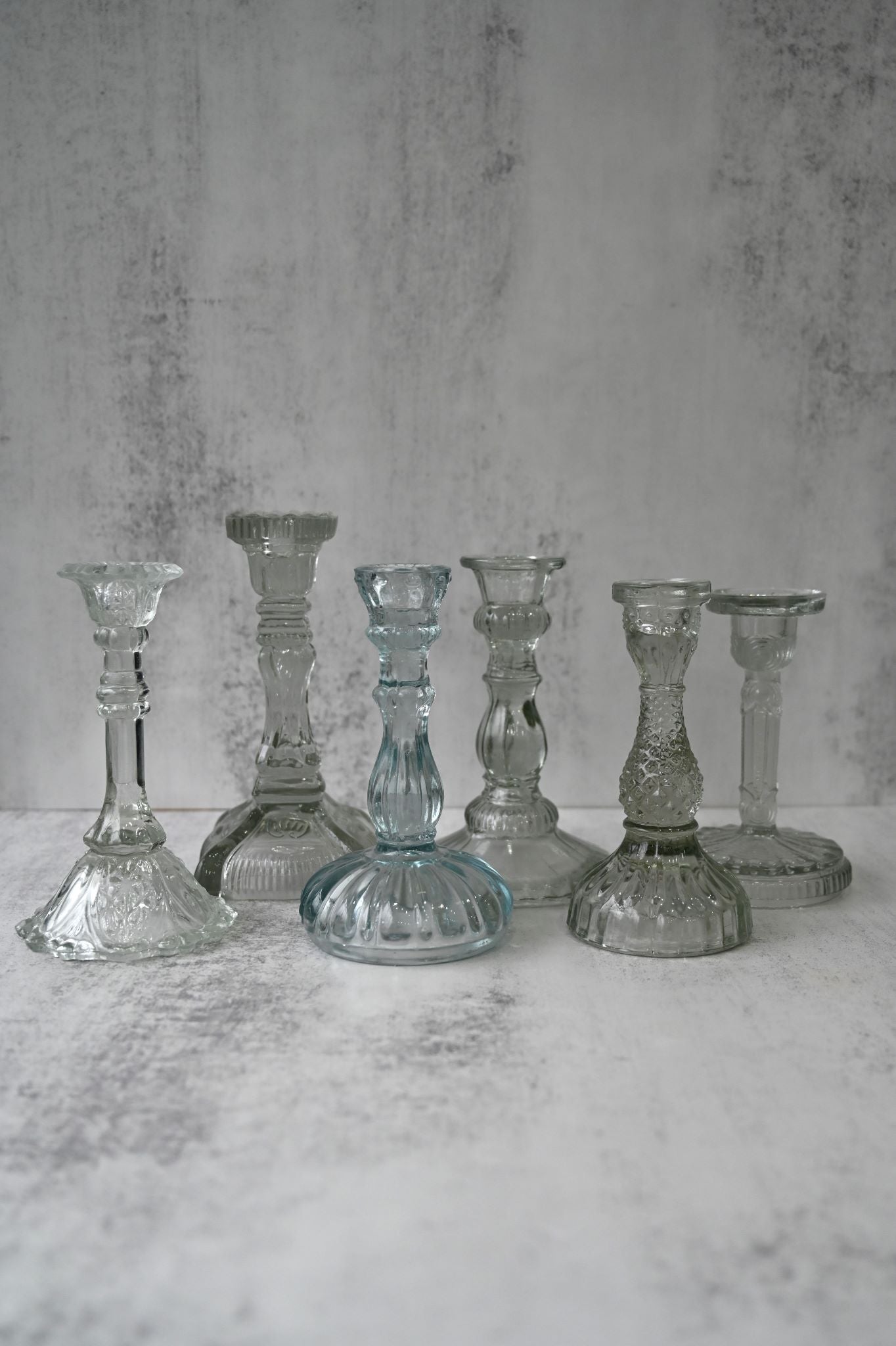 Six mixed vintage style clear and light blue pressed glass taper candle holders.