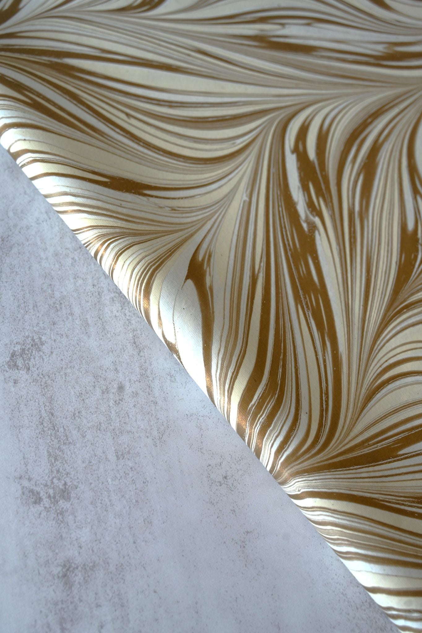Close-up of metallic gold and ivory swirling hand-marbled recycled gift wrap.