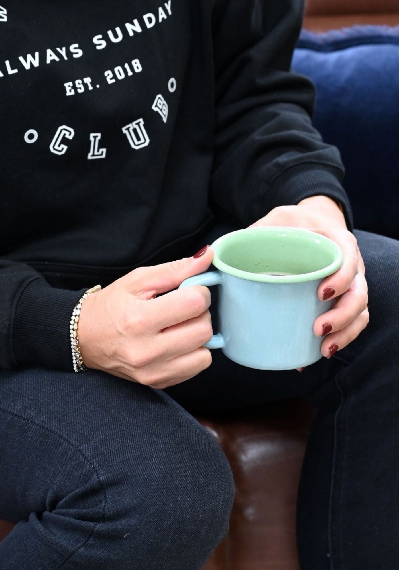 Hand holding large Bath Blue enamel mug with pea green interior.