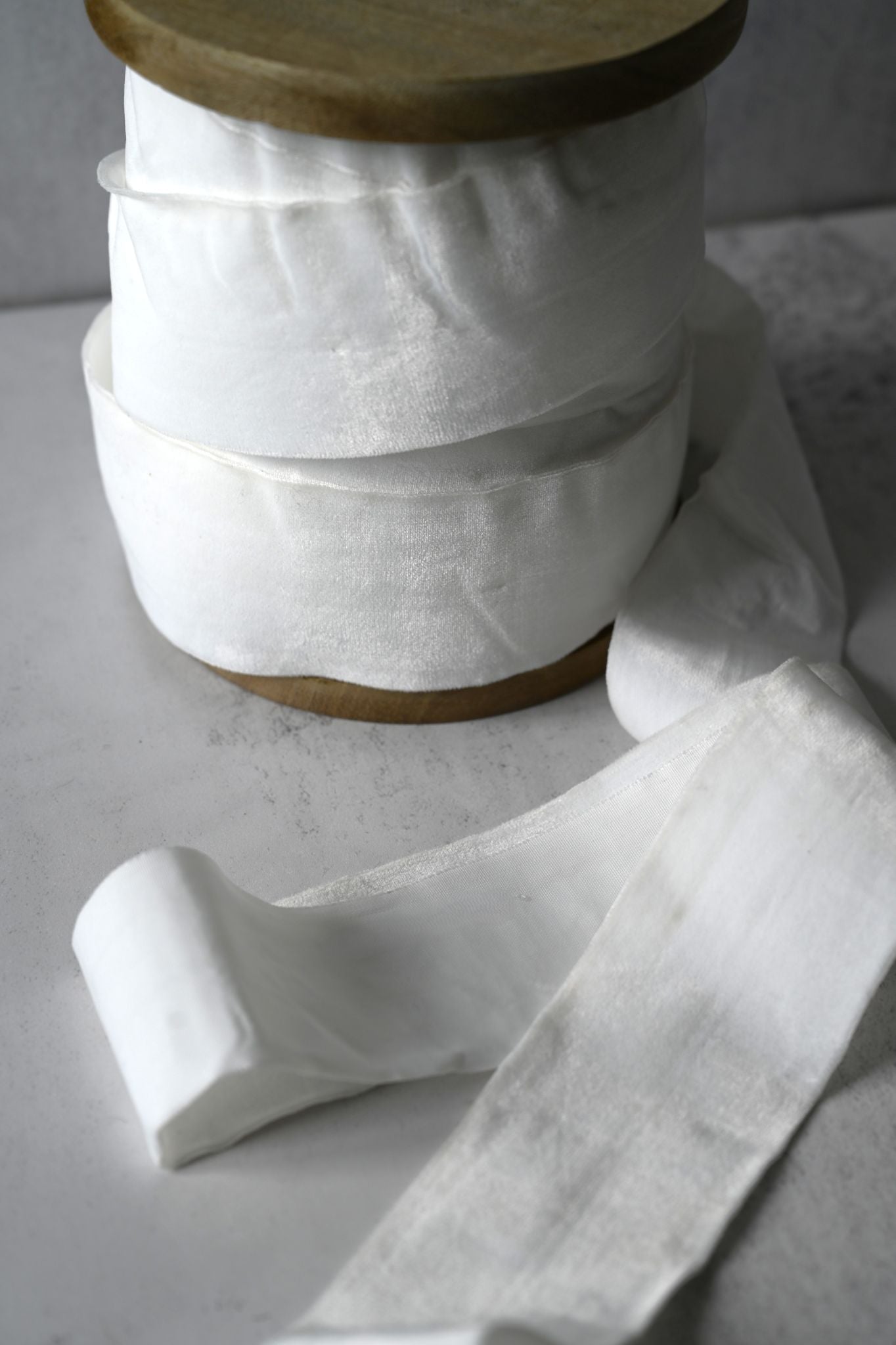 Spool of wide, creamy white cotton velvet ribbon for wedding gift wrapping.