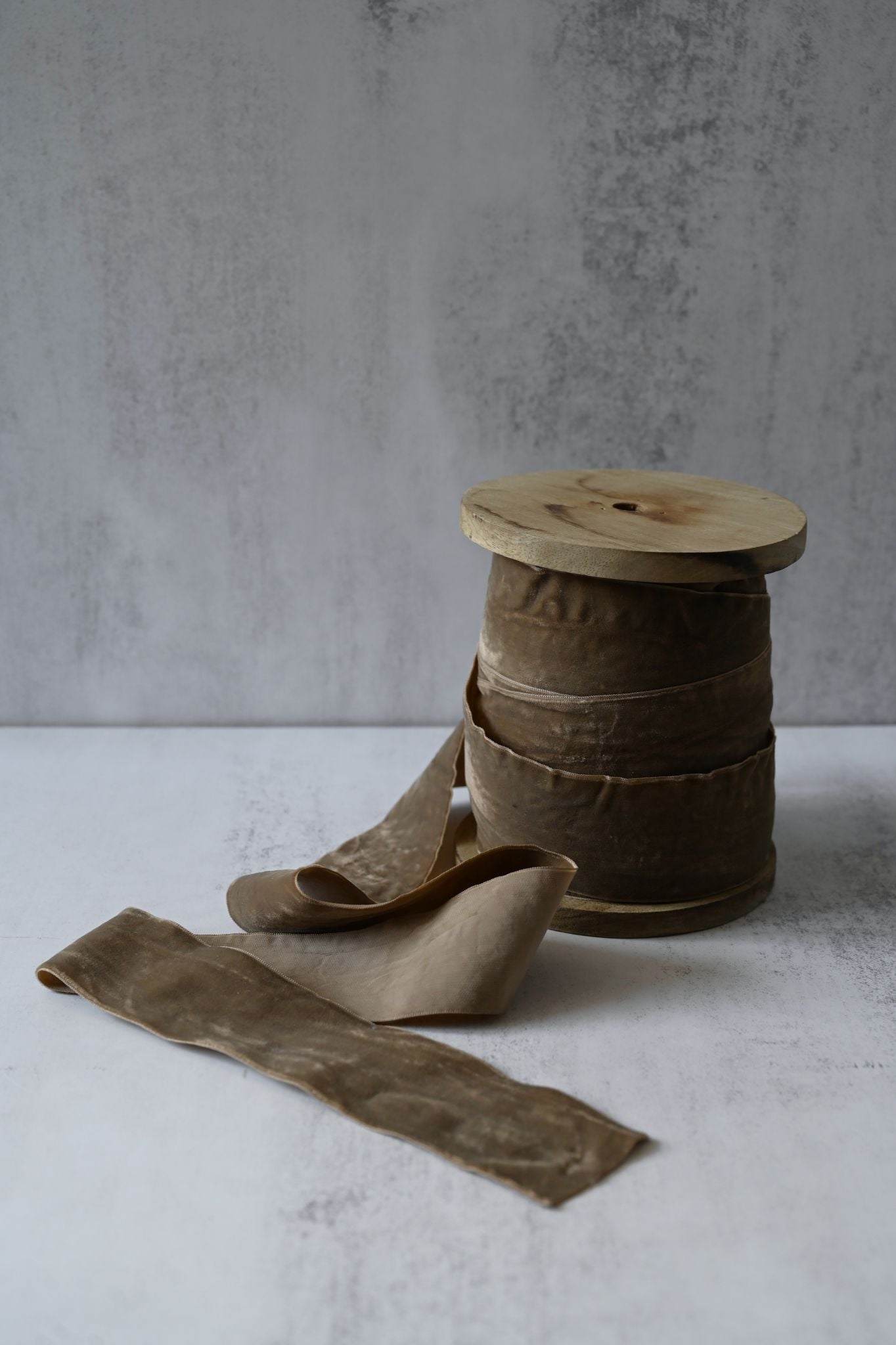 Wide mouse brown cotton velvet ribbon wrapped around a rustic wooden spool.