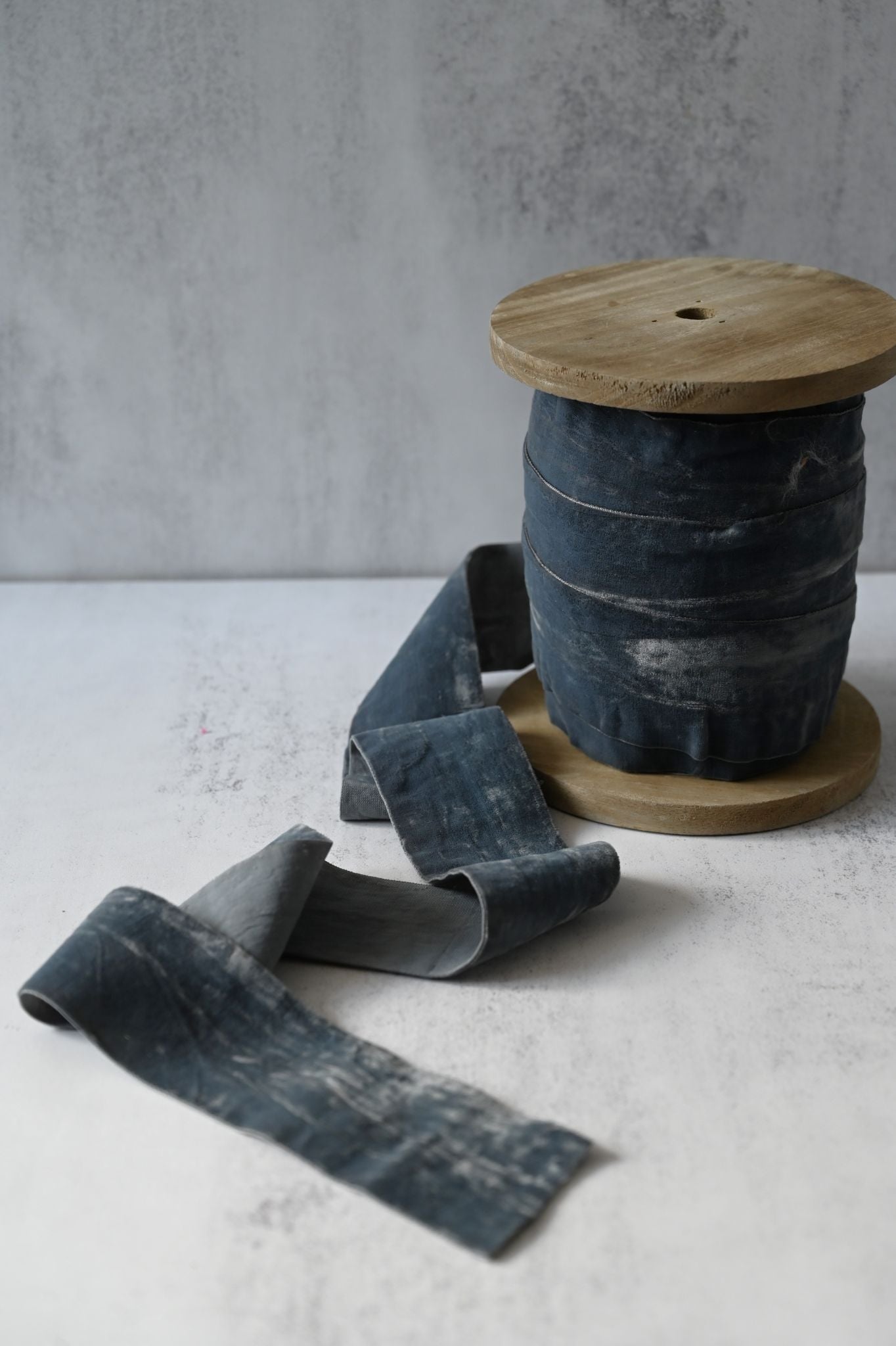 Roll of wide, crushed light grey cotton velvet ribbon on a wooden spool.