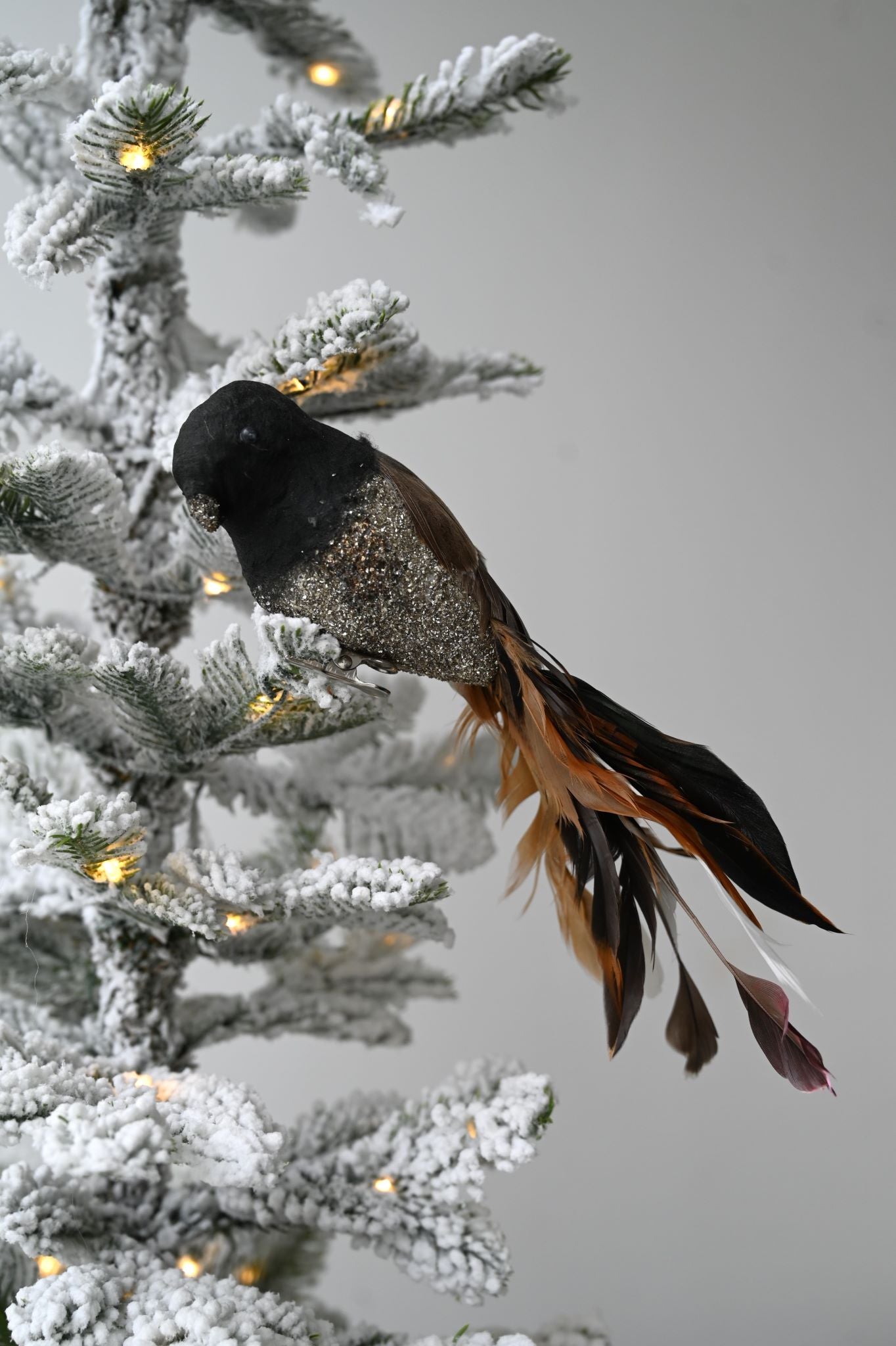 Decorative clip-on bird ornament with black feathers and silver glitter body.